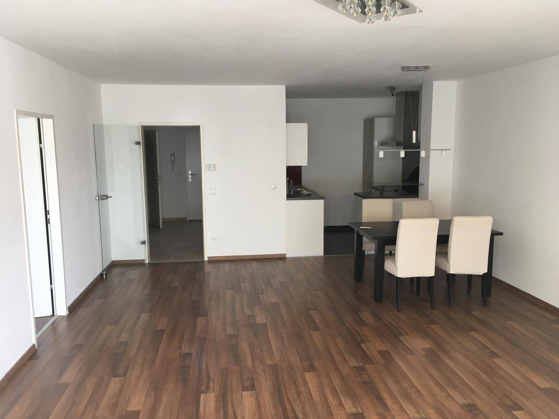 Offener Wohn-Essbereich mit integrierter Küchenzeile und durchgehendem Holzboden.