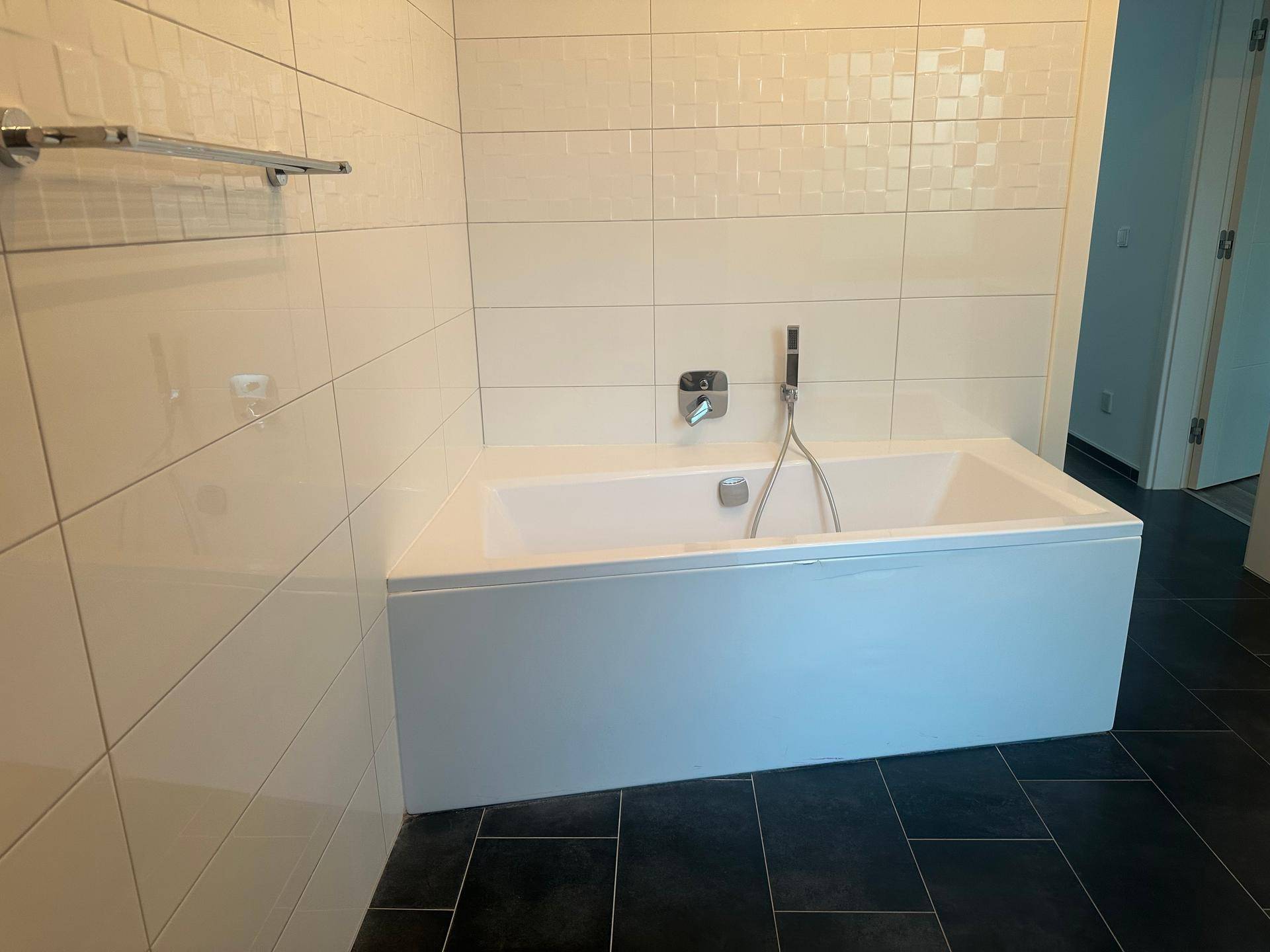 Eingebaute Badewanne mit weißen Fliesen und moderner Armatur im Badezimmer.