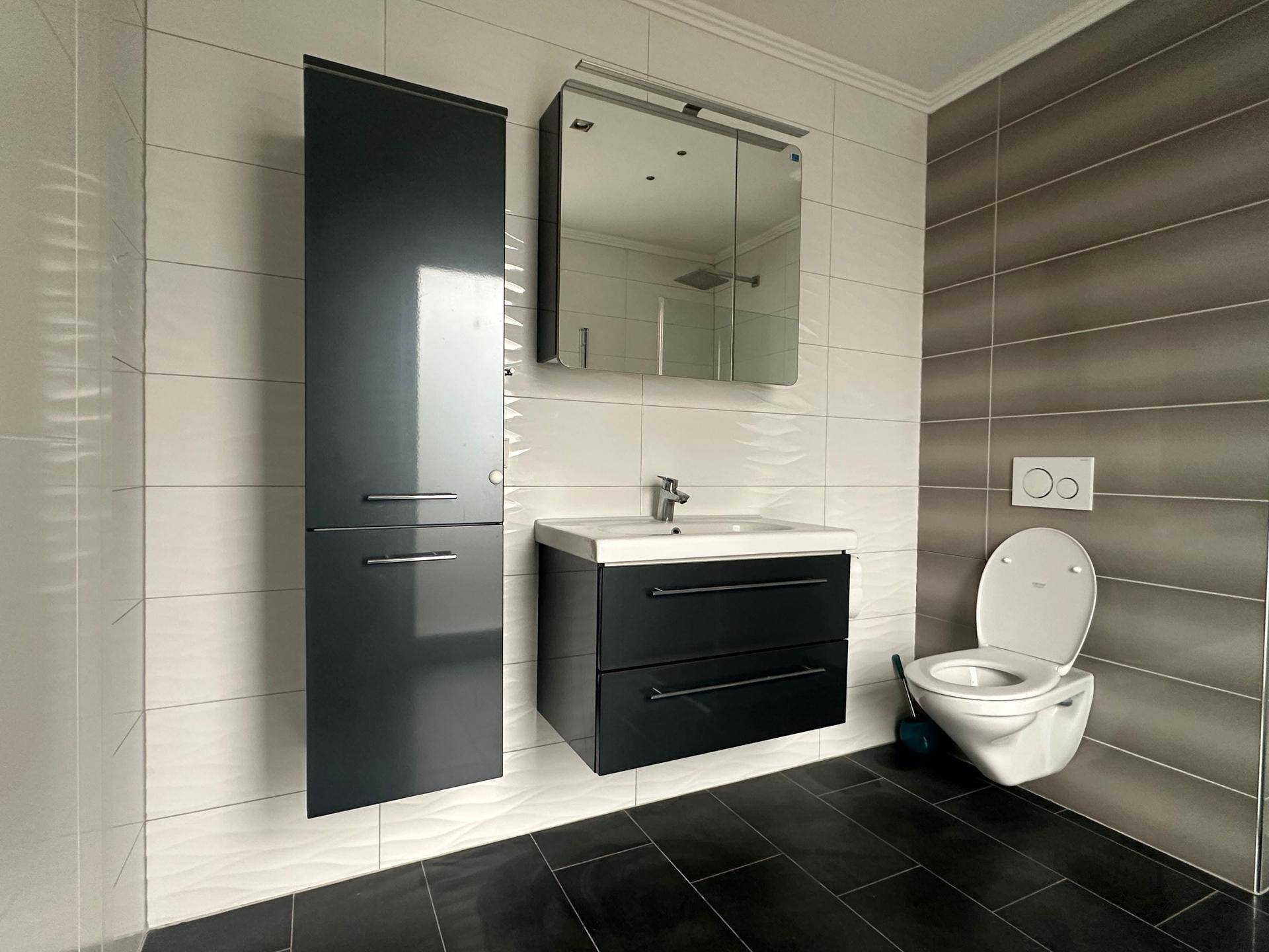 Modernes Badezimmer mit wandhängendem WC, Waschbecken und Spiegelschrank.