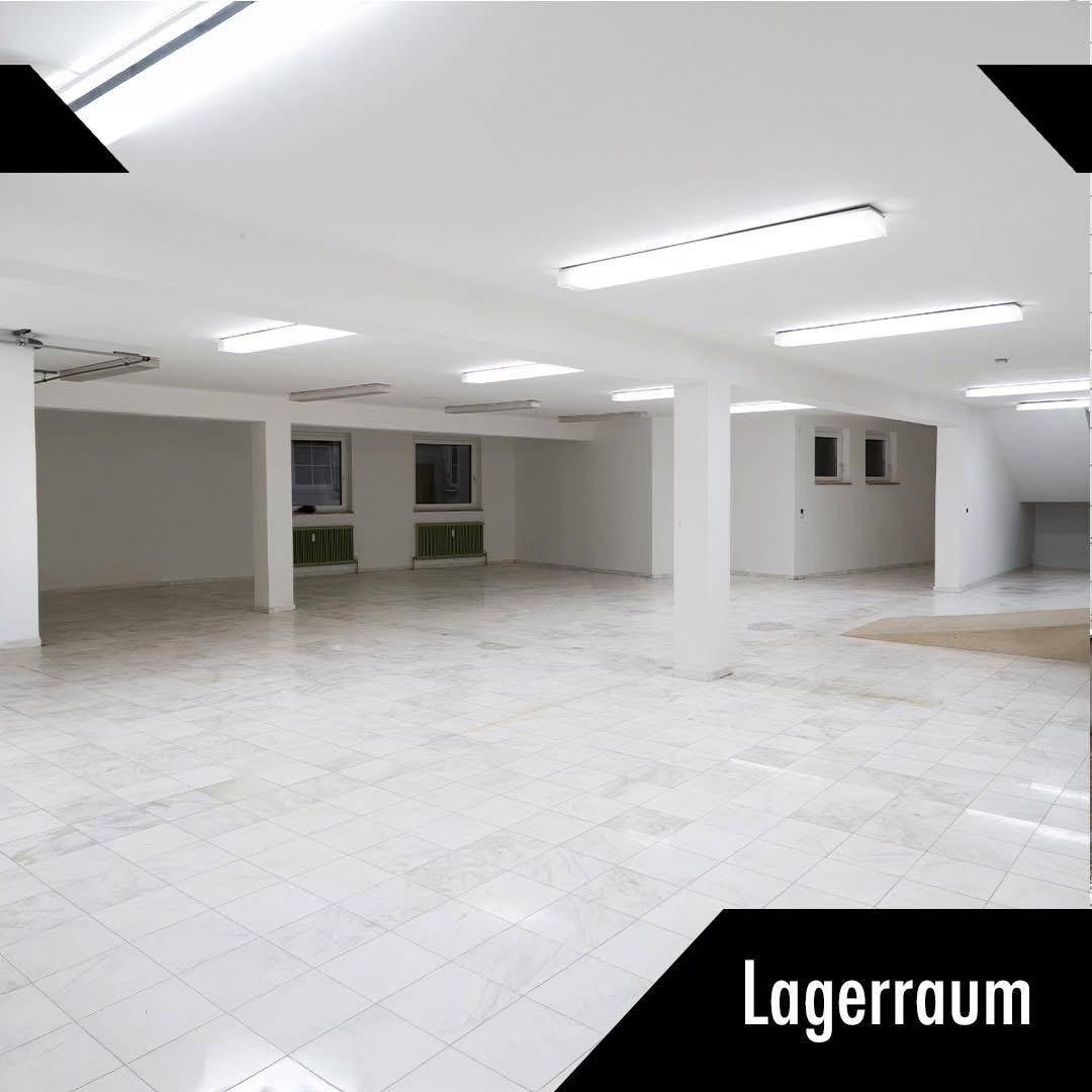 Großer, leerer Lagerraum mit weißen Wänden, Fliesenboden und mehreren Fenstern für Tageslicht.