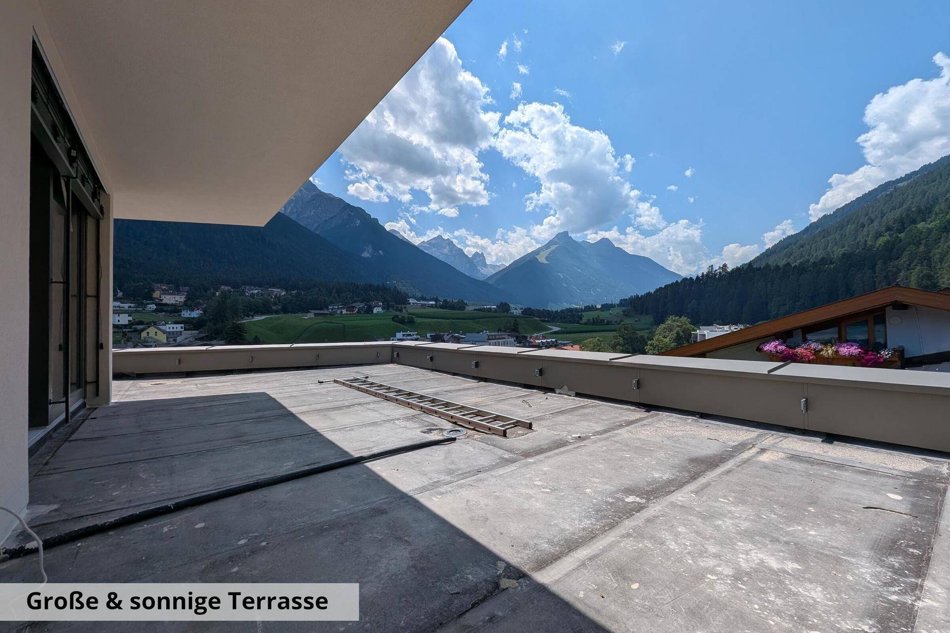 Große, sonnige Terrasse im Rohbau mit beeindruckendem Panoramablick auf die umliegende Bergwelt.