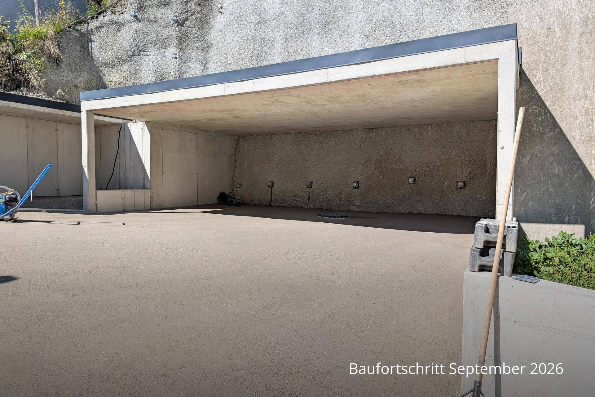Unfertige Betonkonstruktion, möglicherweise ein Carport oder eine offene Garage, in Hanglage.