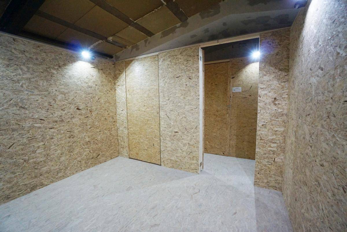Leerer Lagerraum mit hellen OSB-Plattenwänden und glattem Betonboden, bereit zur Nutzung.