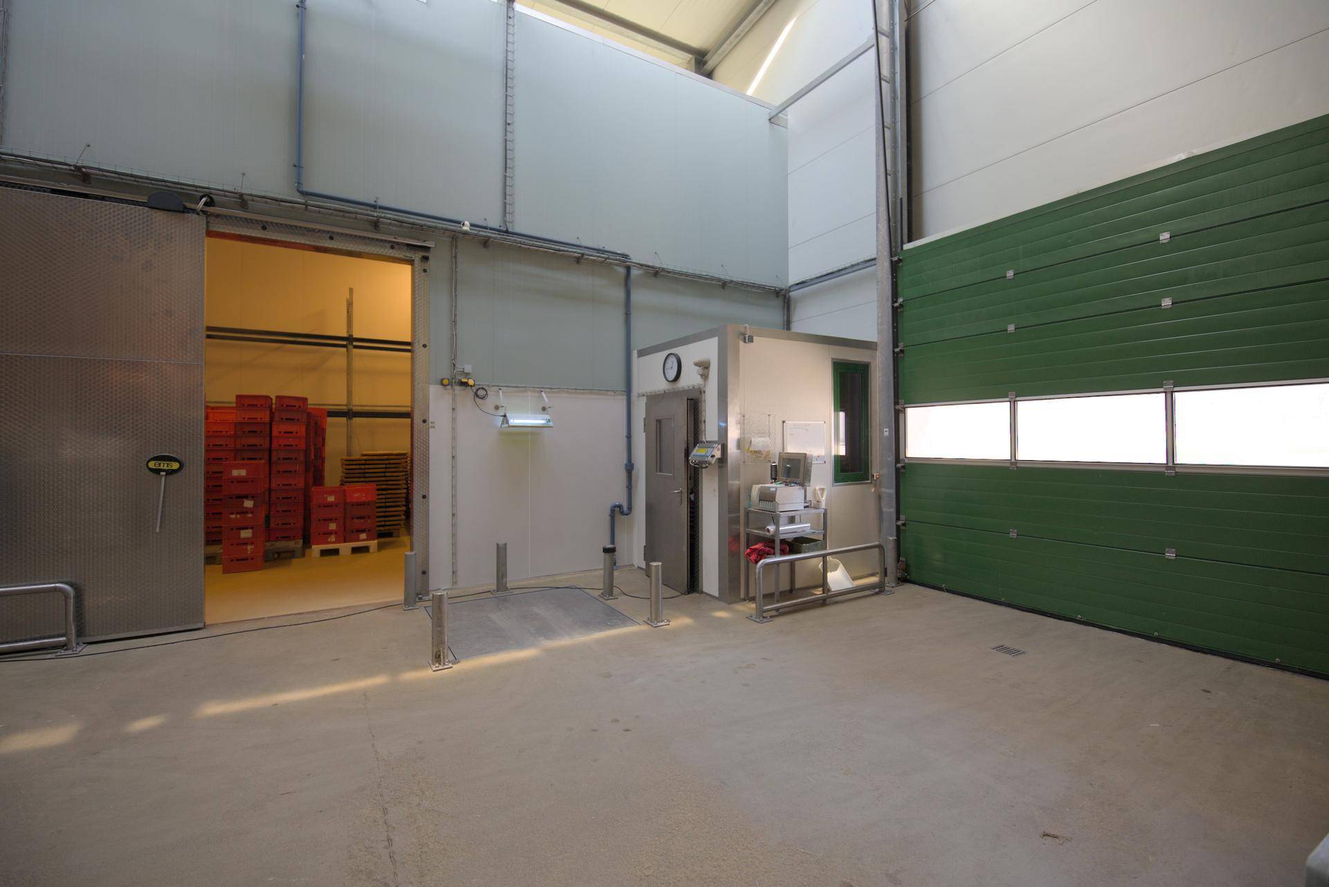 Blick in eine helle Lagerhalle mit geöffnetem Schiebetor, das den Zugang zu weiteren Lagerbereichen freigibt.