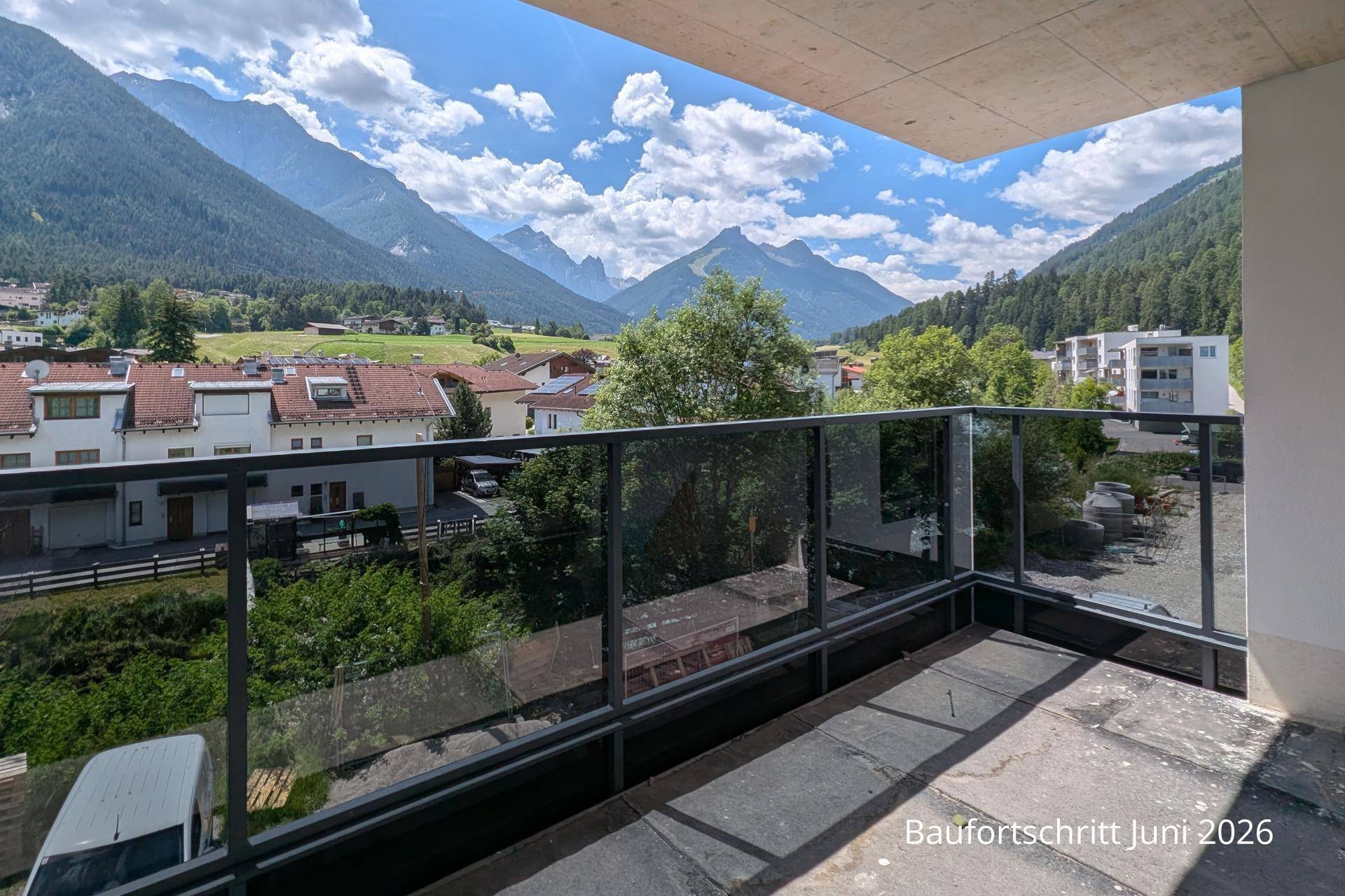 Balkon mit Glasgeländer bietet einen weiten Blick auf die umliegende Berglandschaft und das Tal.