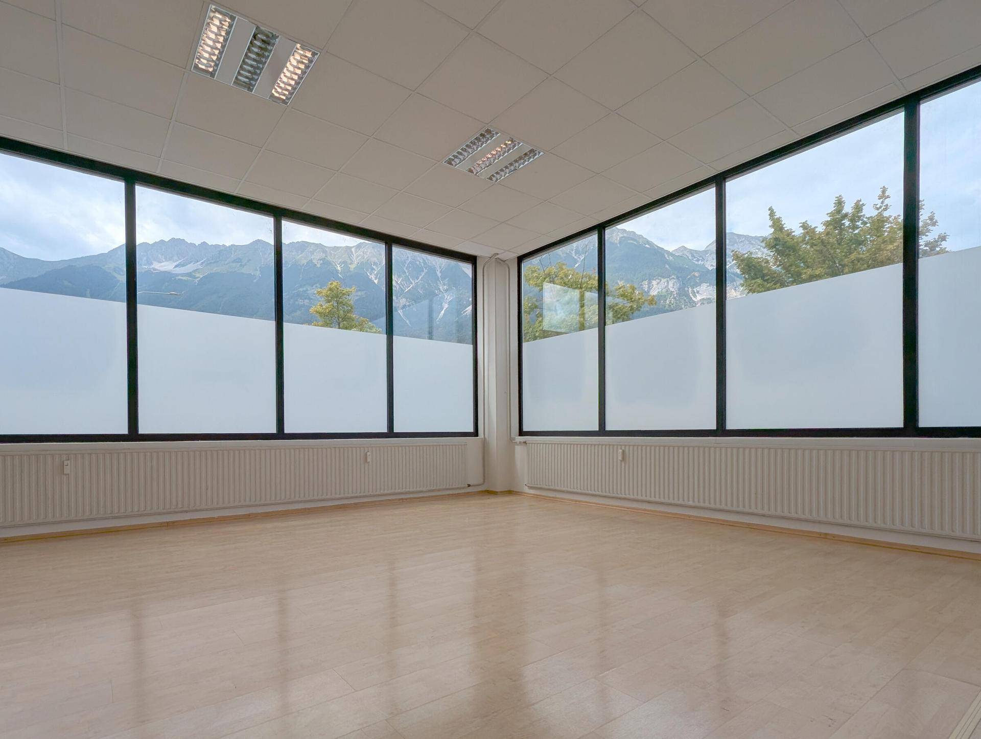Heller Büroraum mit großen Fenstern, die einen beeindruckenden Blick auf die Berge bieten.