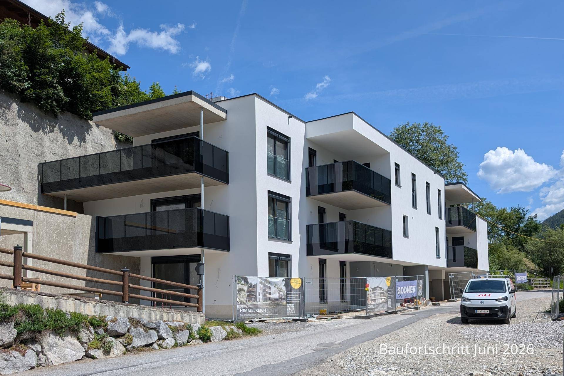 Moderne Architektur des Neubaus mit weißen Fassaden und eleganten Glasbalkonen.