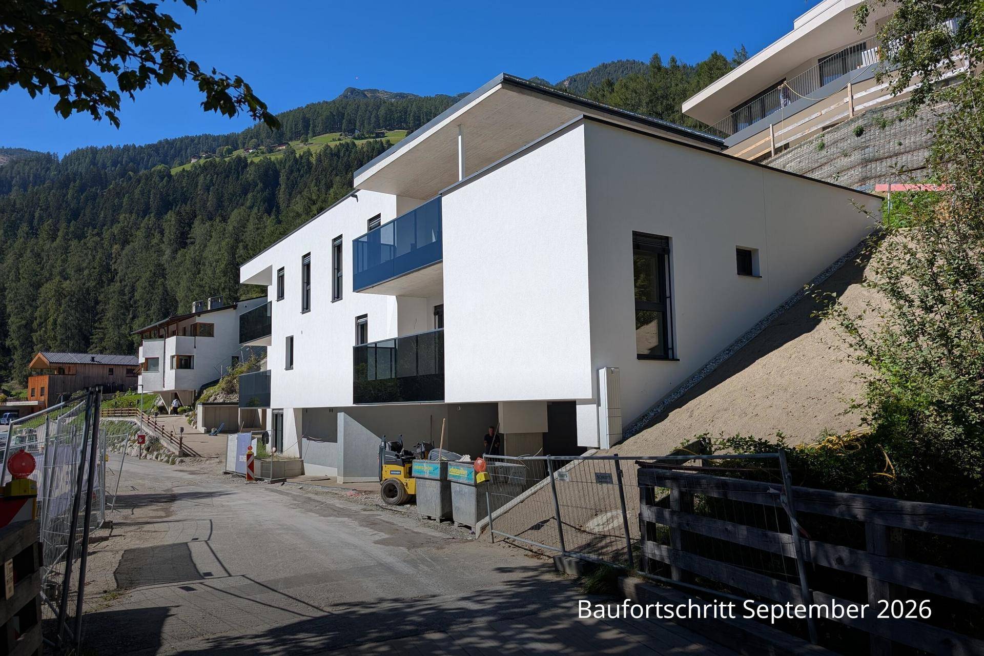 Fortschritt des modernen Neubaus mit Balkonen und beeindruckendem Bergpanorama.