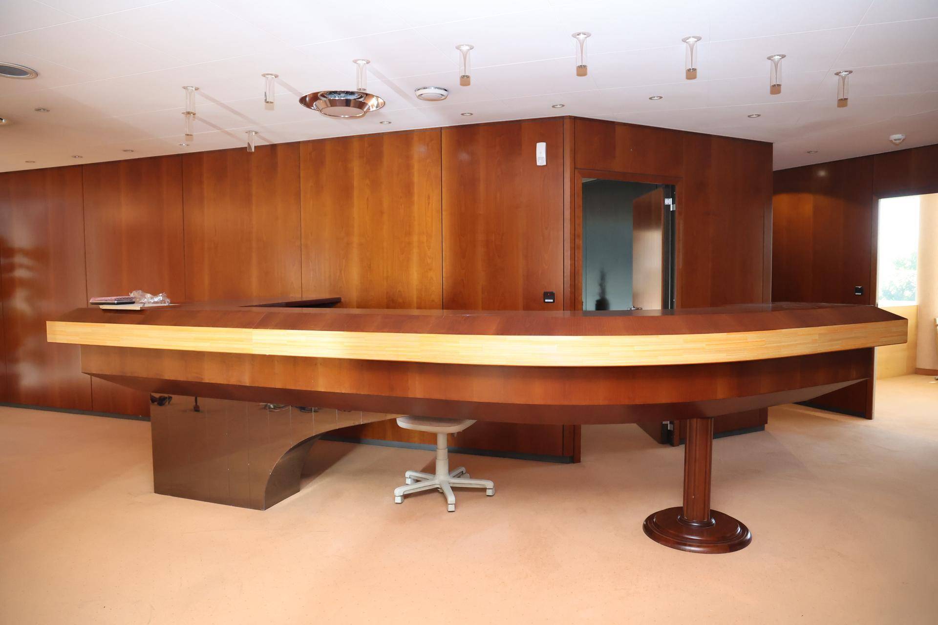 Empfangsbereich mit einer großen, geschwungenen Holztheke und eleganten Holzvertäfelungen an den Wänden.