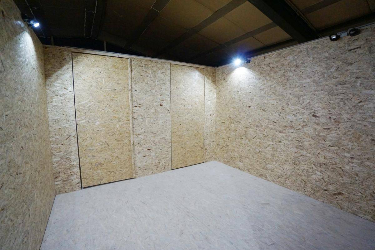 Geräumiger, leerer Lagerraum mit OSB-Plattenverkleidung und robustem Betonboden, gut beleuchtet.