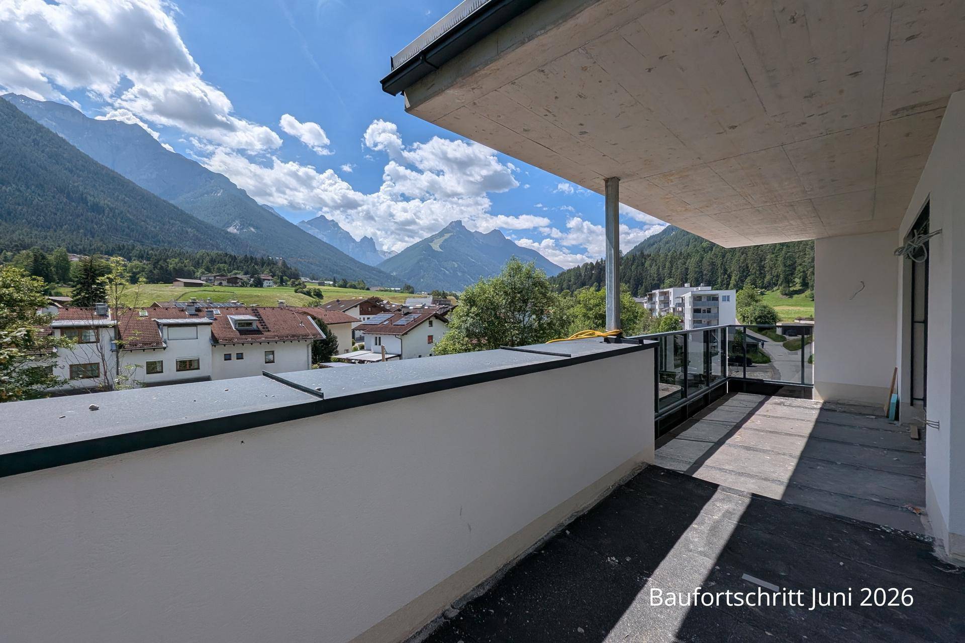 Weitläufige Terrasse im Rohbau mit weitem Blick auf die majestätische Bergwelt und das Tal.