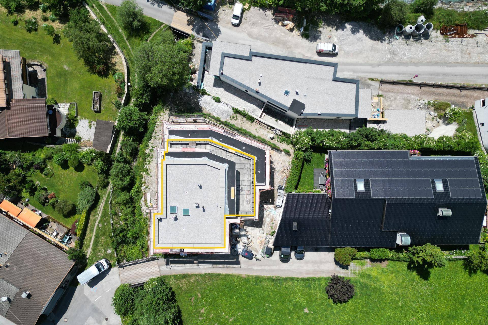 Vogelperspektive des Grundstücks mit Neubau und umliegender grüner Landschaft.