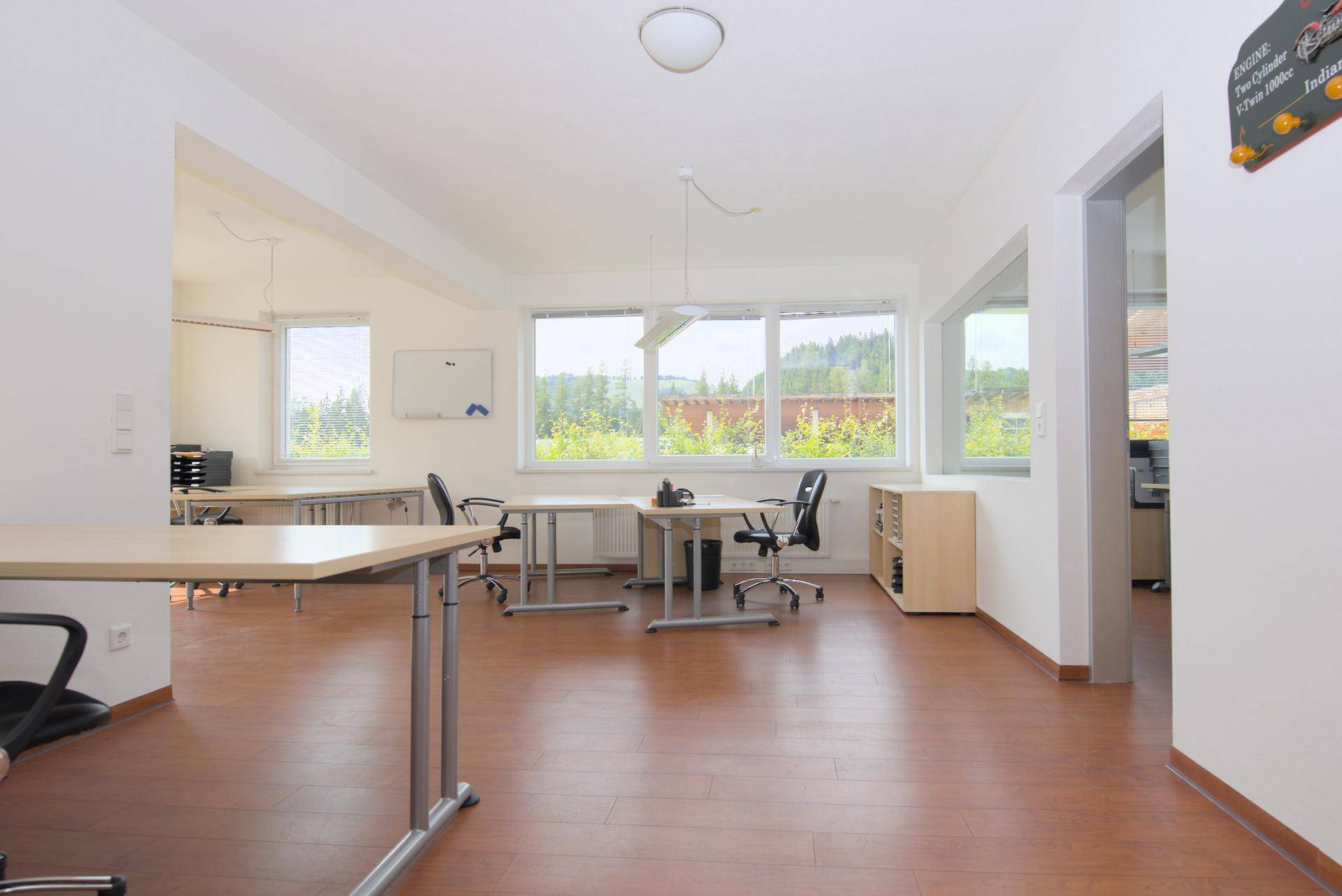Helles und geräumiges Büro mit Holzboden, modernen Möbeln und weitem Blick ins Grüne.