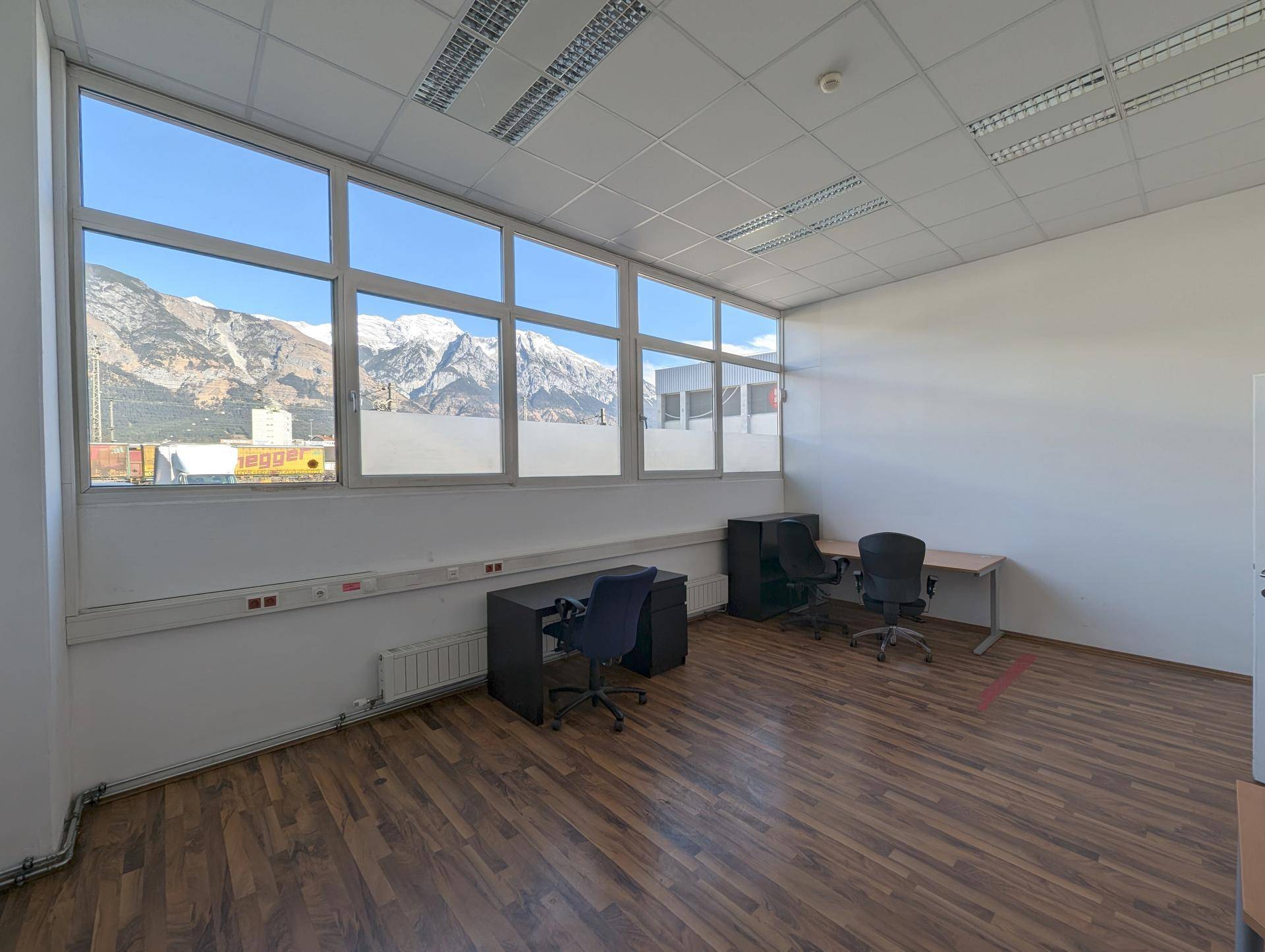 Helles Büro mit Laminatboden und großen Fenstern, die einen beeindruckenden Bergblick ermöglichen.