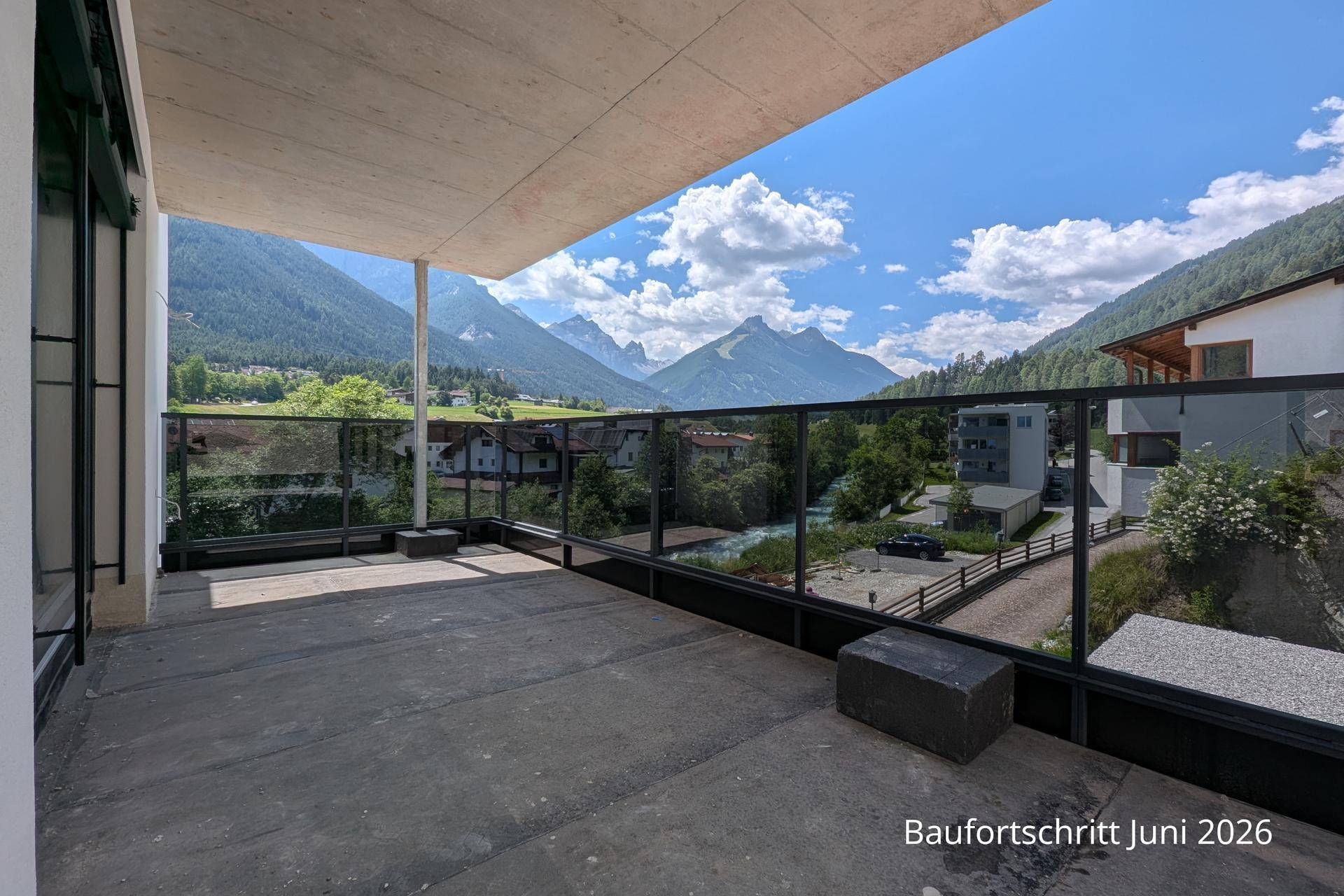 Geräumiger Balkon mit Glasbrüstung und atemberaubendem Blick auf die umliegende Berglandschaft.