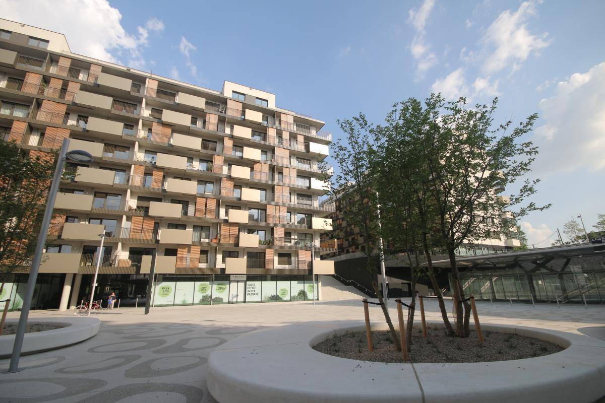 Moderne Wohnanlage mit mehreren Etagen und begrüntem Vorplatz.