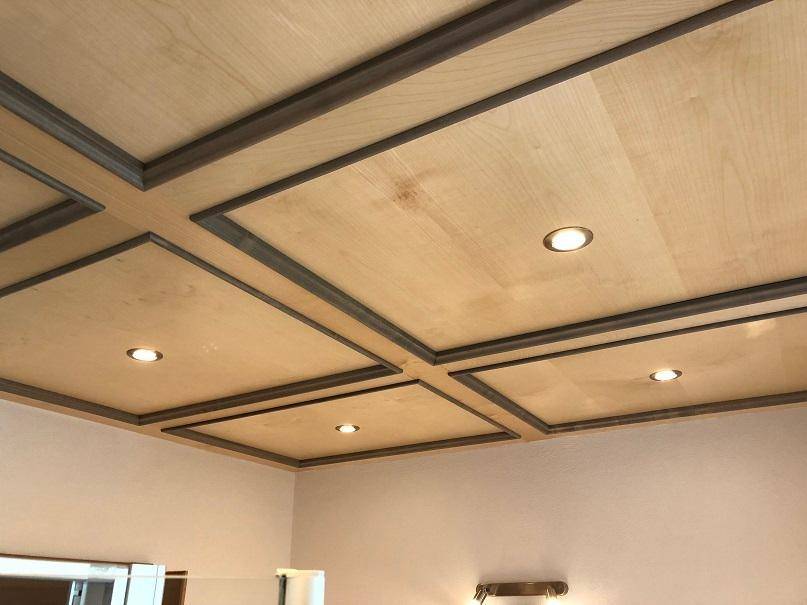 Deckenansicht mit Holzpaneelen und integrierten Einbaustrahlern, die für indirekte Beleuchtung sorgen.