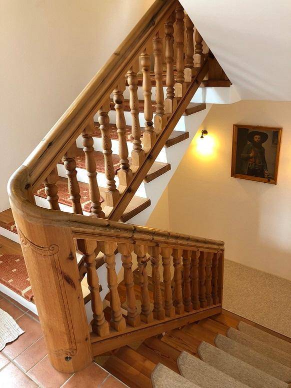 Traditionelle Holztreppe mit geschnitztem Geländer, die die Stockwerke miteinander verbindet.