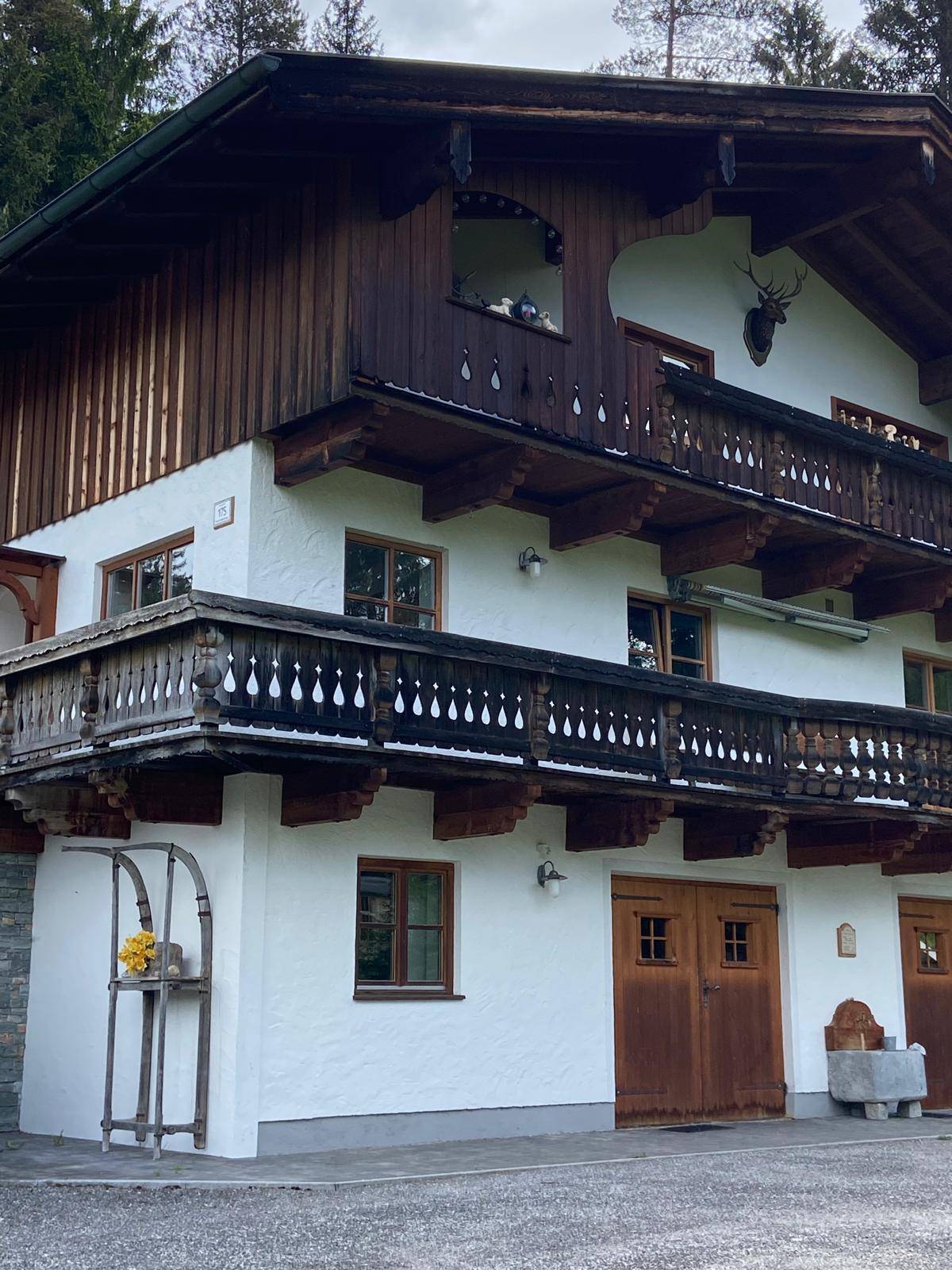 Detailansicht der traditionellen Holzbalustraden und Fenster des Alpenhauses mit Hirschgeweih-Dekoration.
