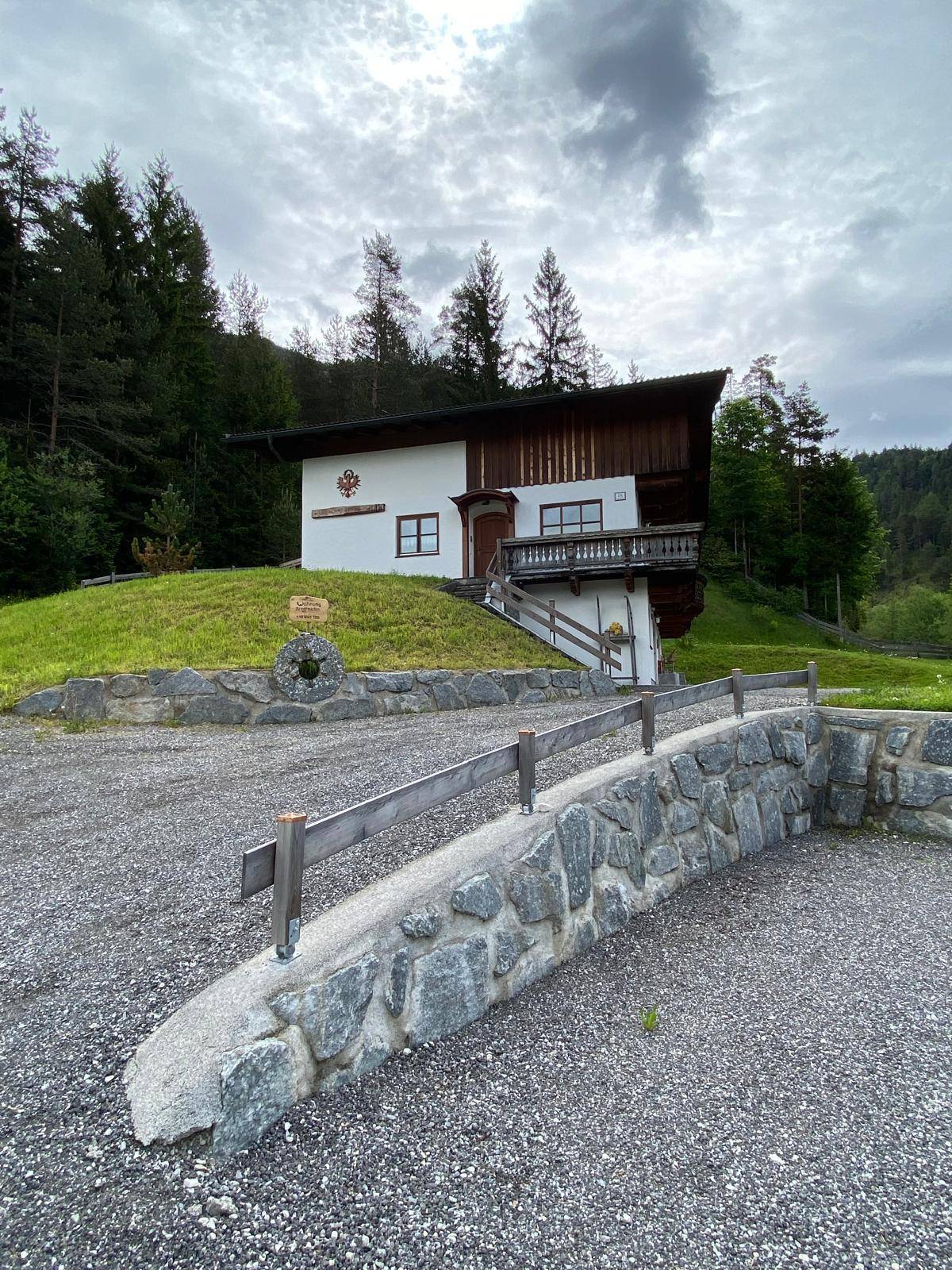 Traditionelles Alpenhaus mit Holzbalkonen und grüner Umgebung, umgeben von Natur.