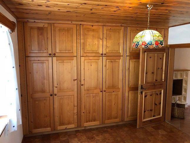 Schlafzimmer mit raumhohen Einbauschränken aus Holz und einer traditionellen Deckenlampe.