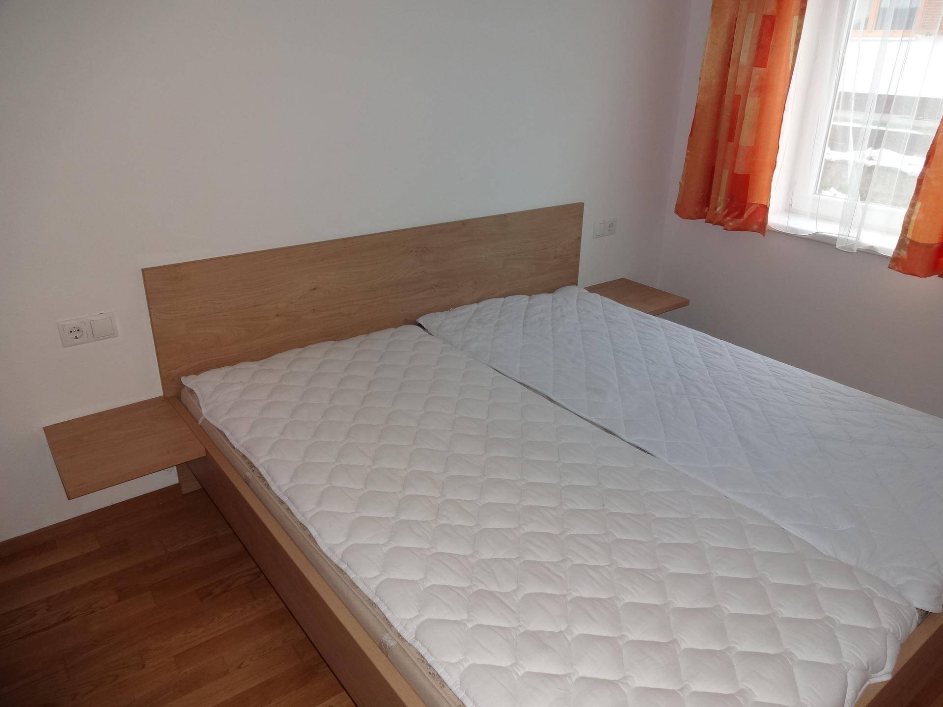Helles Schlafzimmer mit Doppelbett und Nachttischen, ausgestattet mit Holzboden.