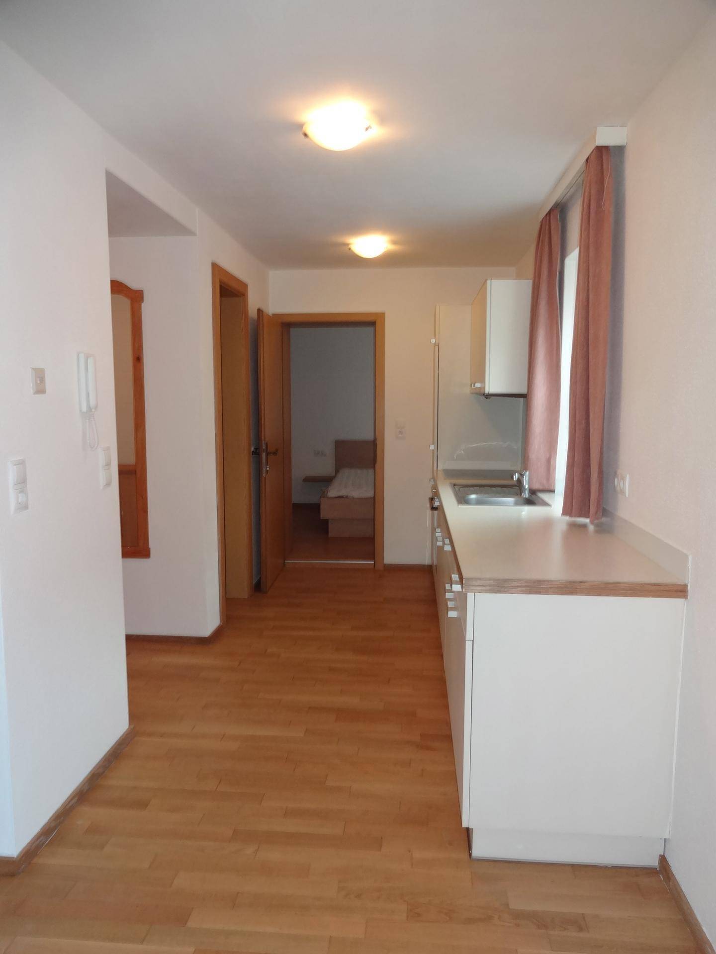 Flur mit Küchenzeile und Zugang zu einem Schlafzimmer, ausgestattet mit Holzboden.