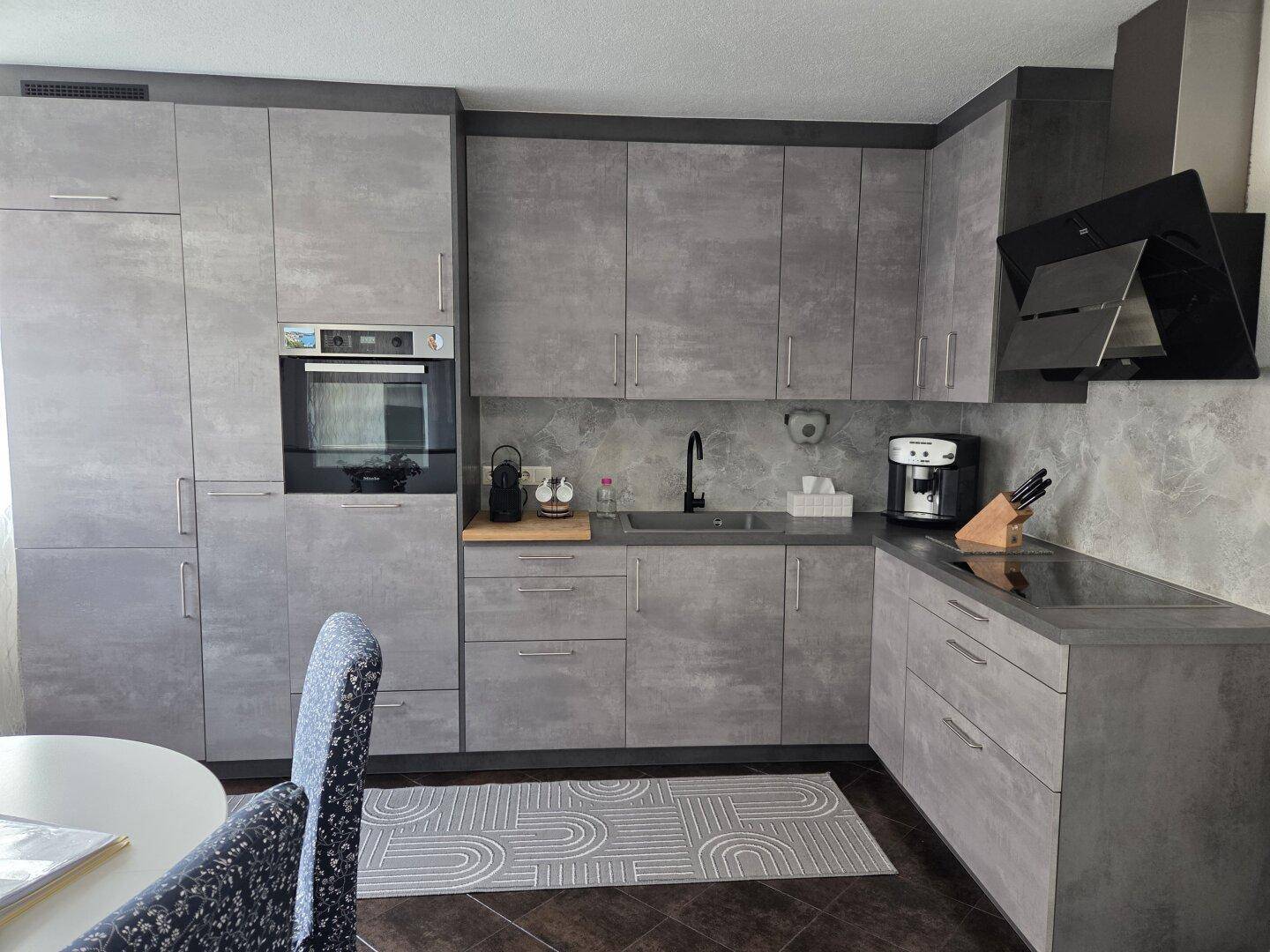 Moderne Einbauküche in Grau mit integrierten Geräten und viel Stauraum.