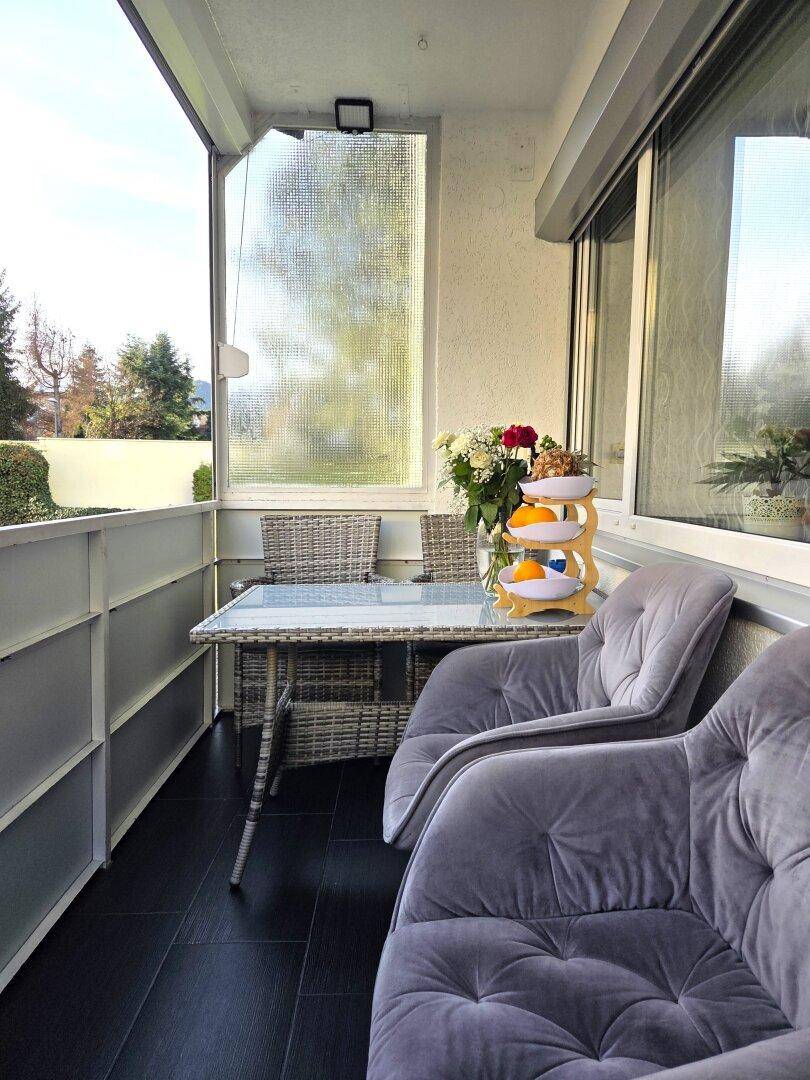 Verglaster Balkon mit Sitzgelegenheiten und Blick ins Grüne.