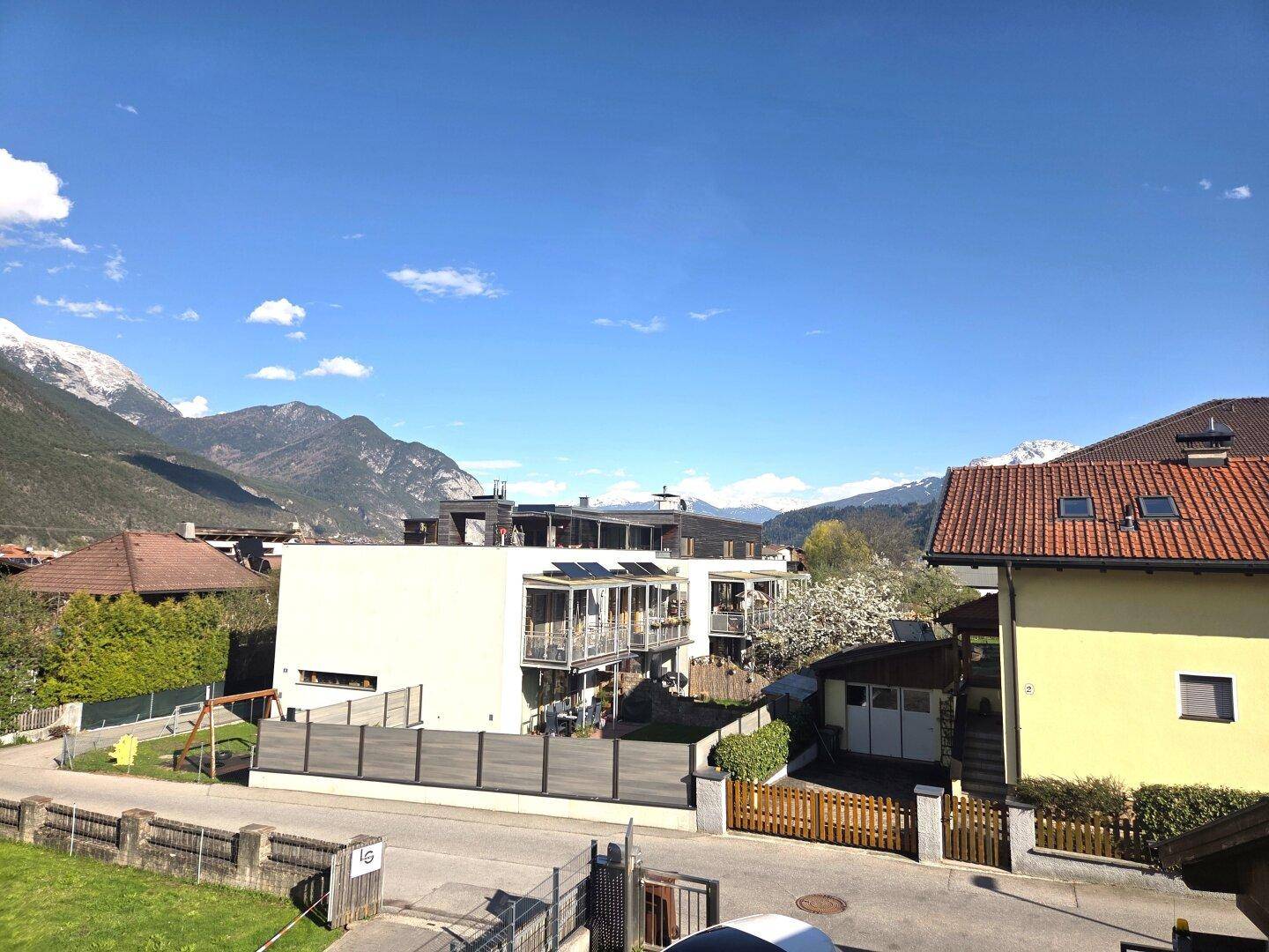 Weitläufiger Blick über die Nachbarschaft mit modernen Häusern und majestätischen Bergen im Hintergrund.