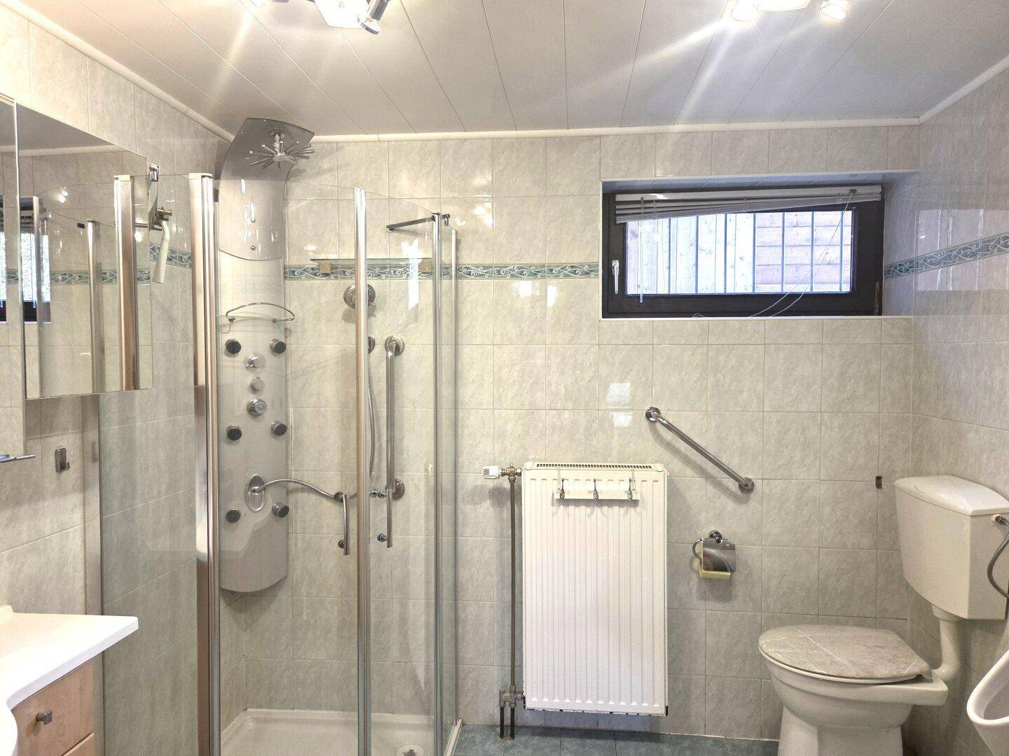 Funktionales Badezimmer mit Duschkabine, Toilette und Fenster für Tageslicht.