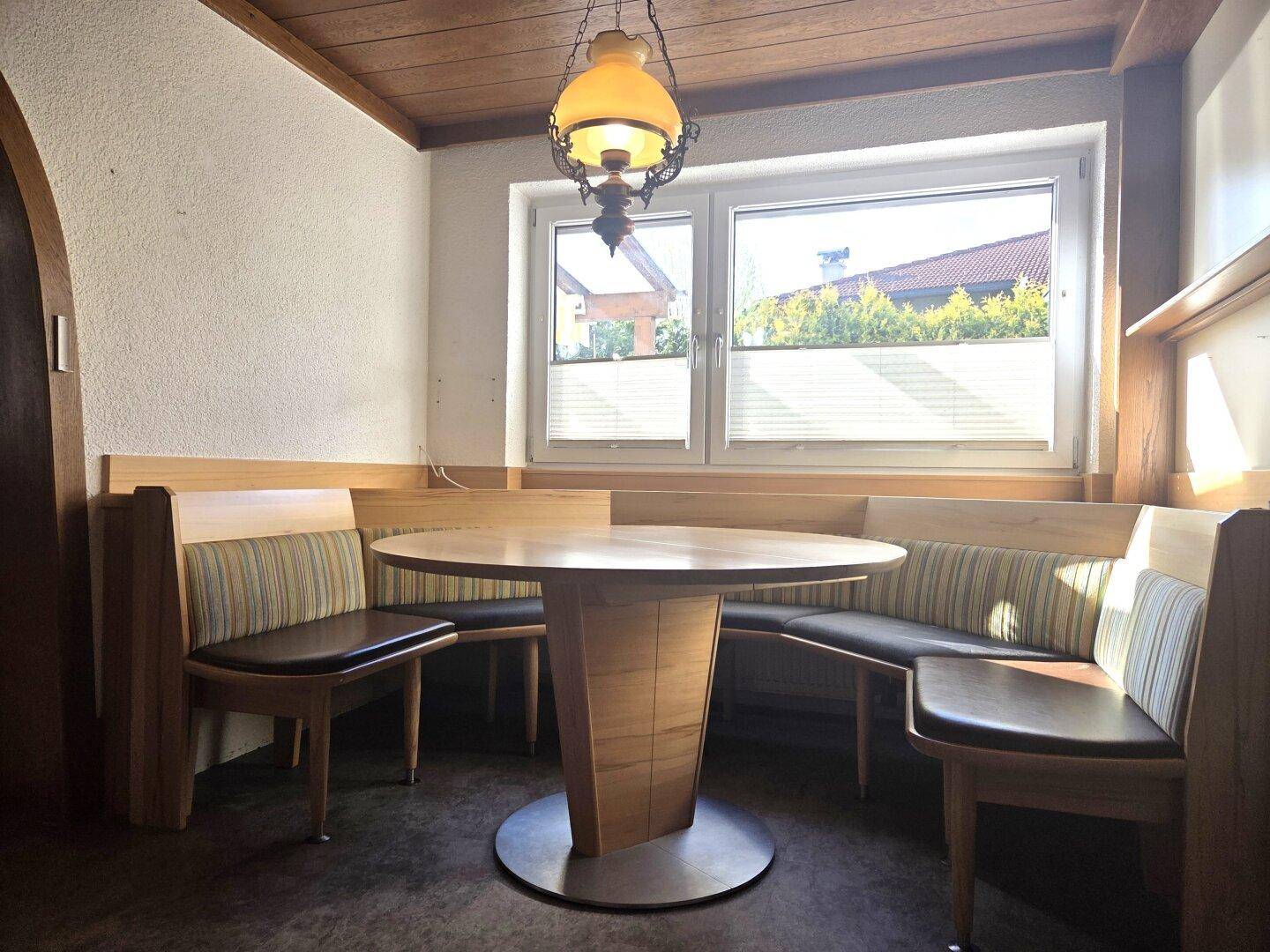 Gemütliche Essecke mit Holzbänken, rundem Tisch und Fenster für natürliches Licht.