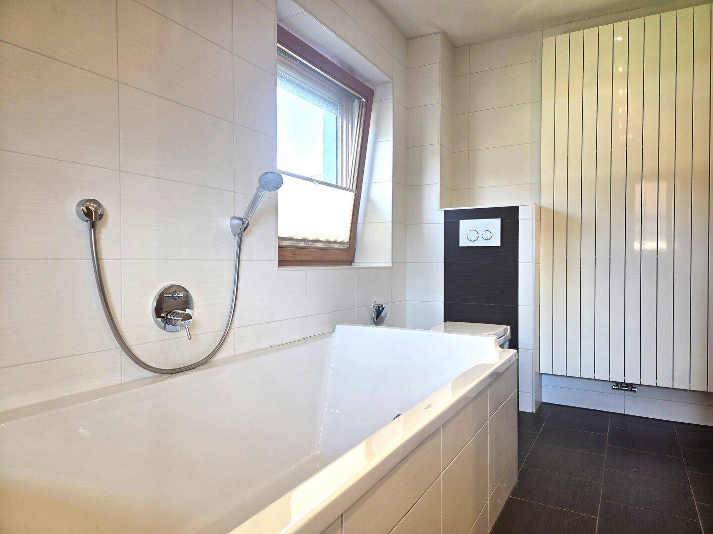 Modernes Badezimmer mit Badewanne, Wand-WC und beheiztem Handtuchhalter.
