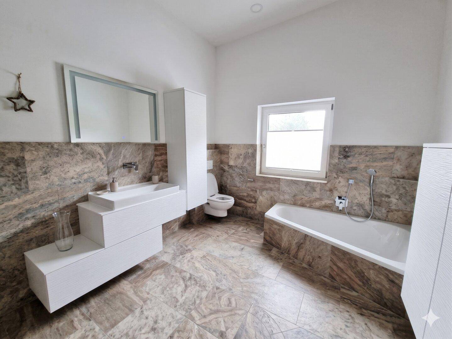 Modernes Badezimmer mit Badewanne, Fenster und eleganten Fliesen.