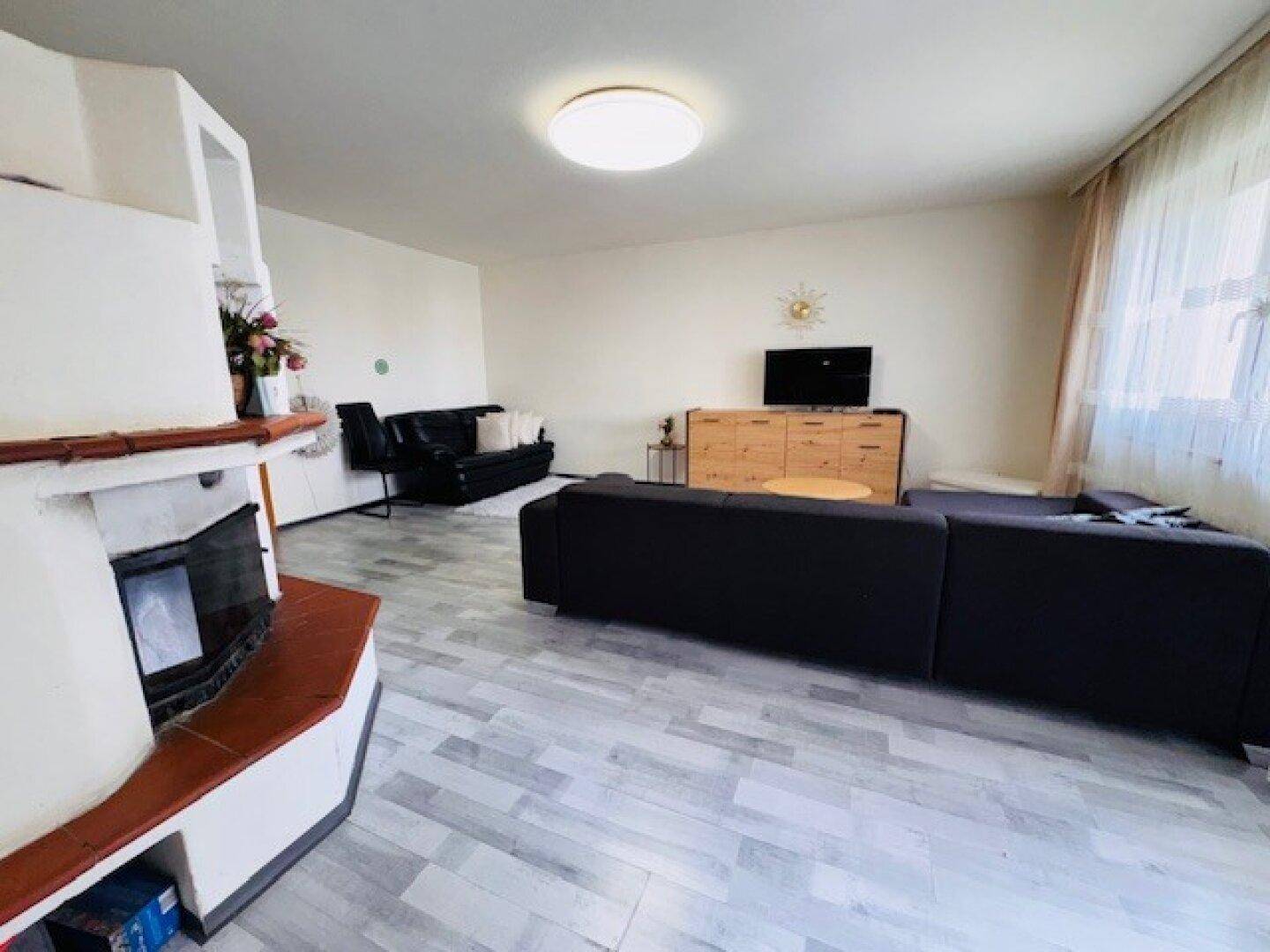 Geräumiges Wohnzimmer mit Kamin, bequemen Sofas und einem Fenster mit Vorhängen.