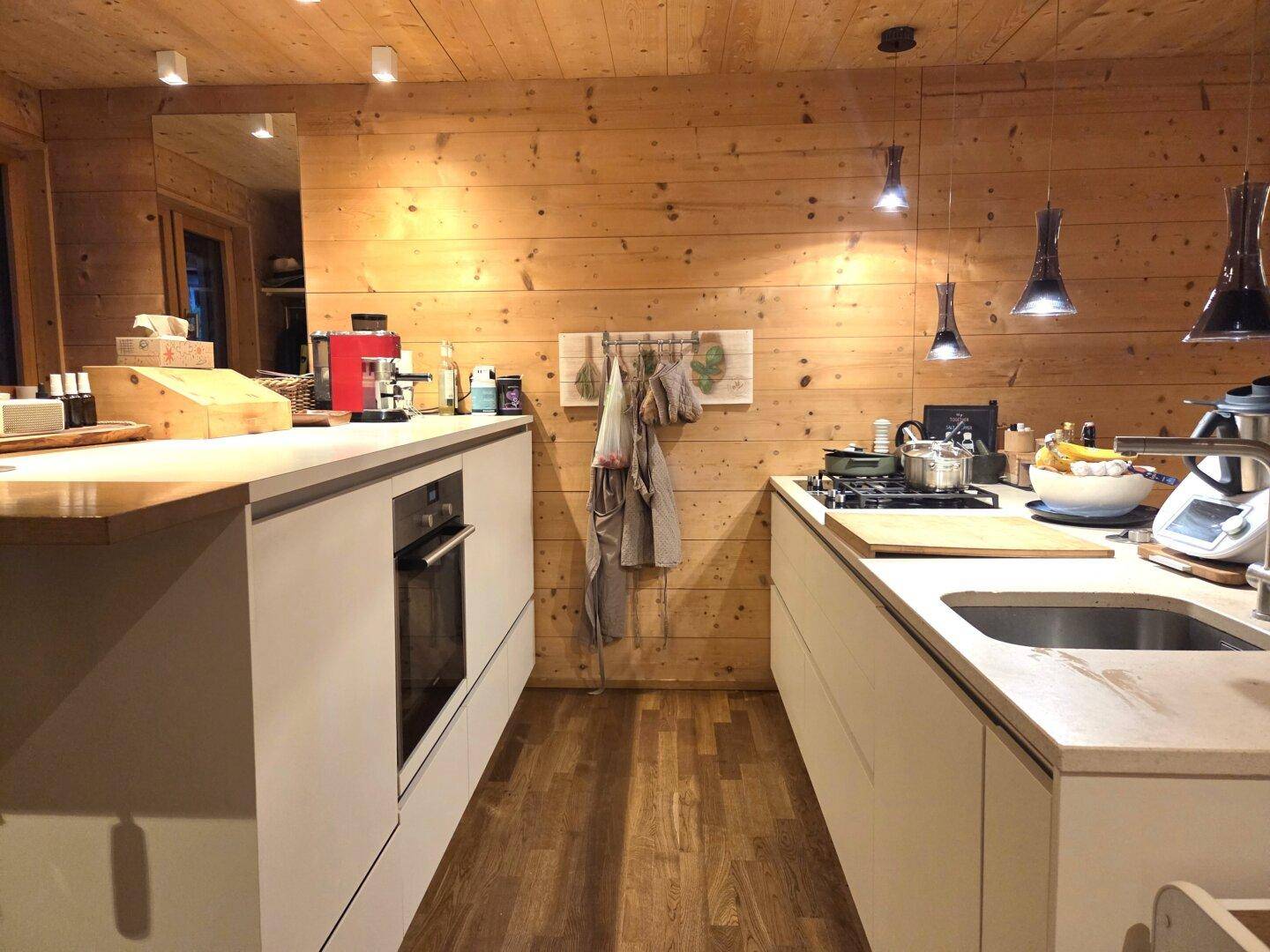 Funktionale Küche mit modernen Einbaugeräten, Holzvertäfelung und ausreichend Arbeitsfläche.