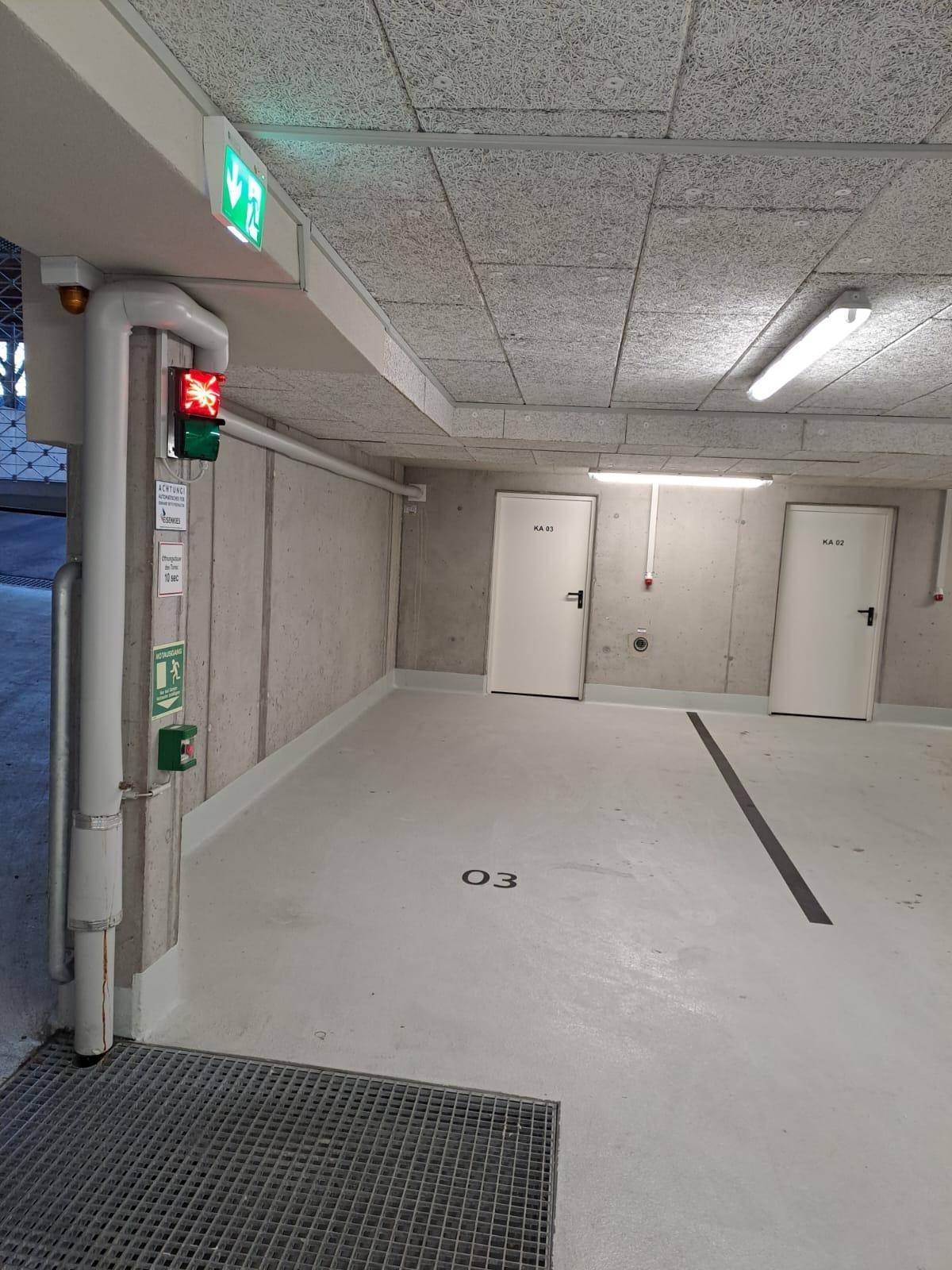 Tiefgaragenstellplatz mit Einfahrt, Betonwänden und Sicherheitsbeleuchtung.