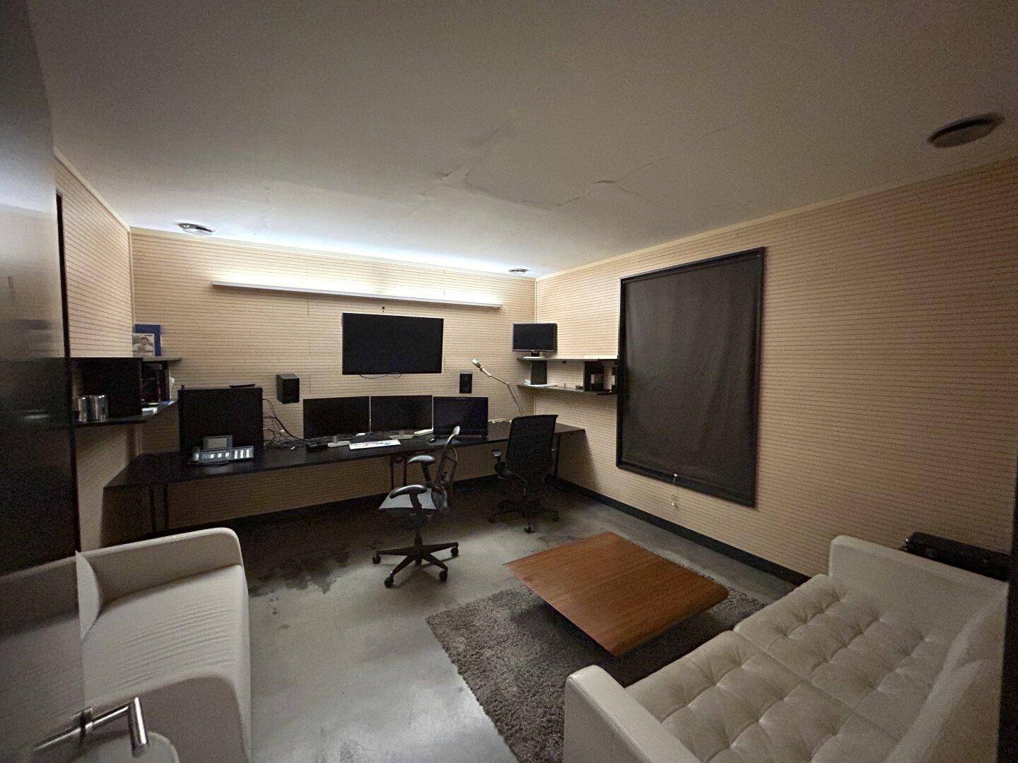 Komfortabler Bürobereich mit Sofas, Schreibtisch und Holzvertäfelung, ideal für entspanntes Arbeiten.