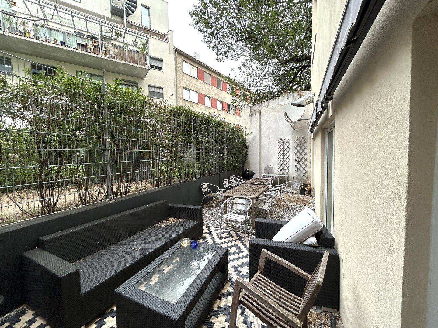 Gemütliche Außenterrasse mit Sitzgelegenheiten, umgeben von Grün und einer Hecke für Privatsphäre.