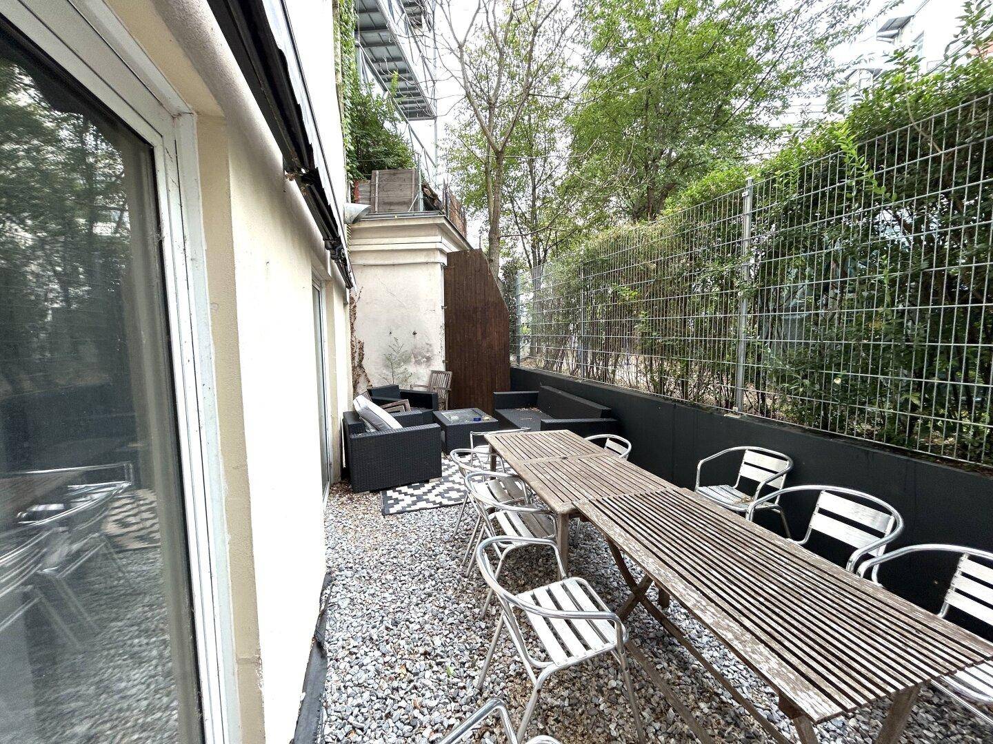 Geräumige Terrasse mit großem Holztisch, Sitzgelegenheiten und direktem Zugang zum Gartenbereich.