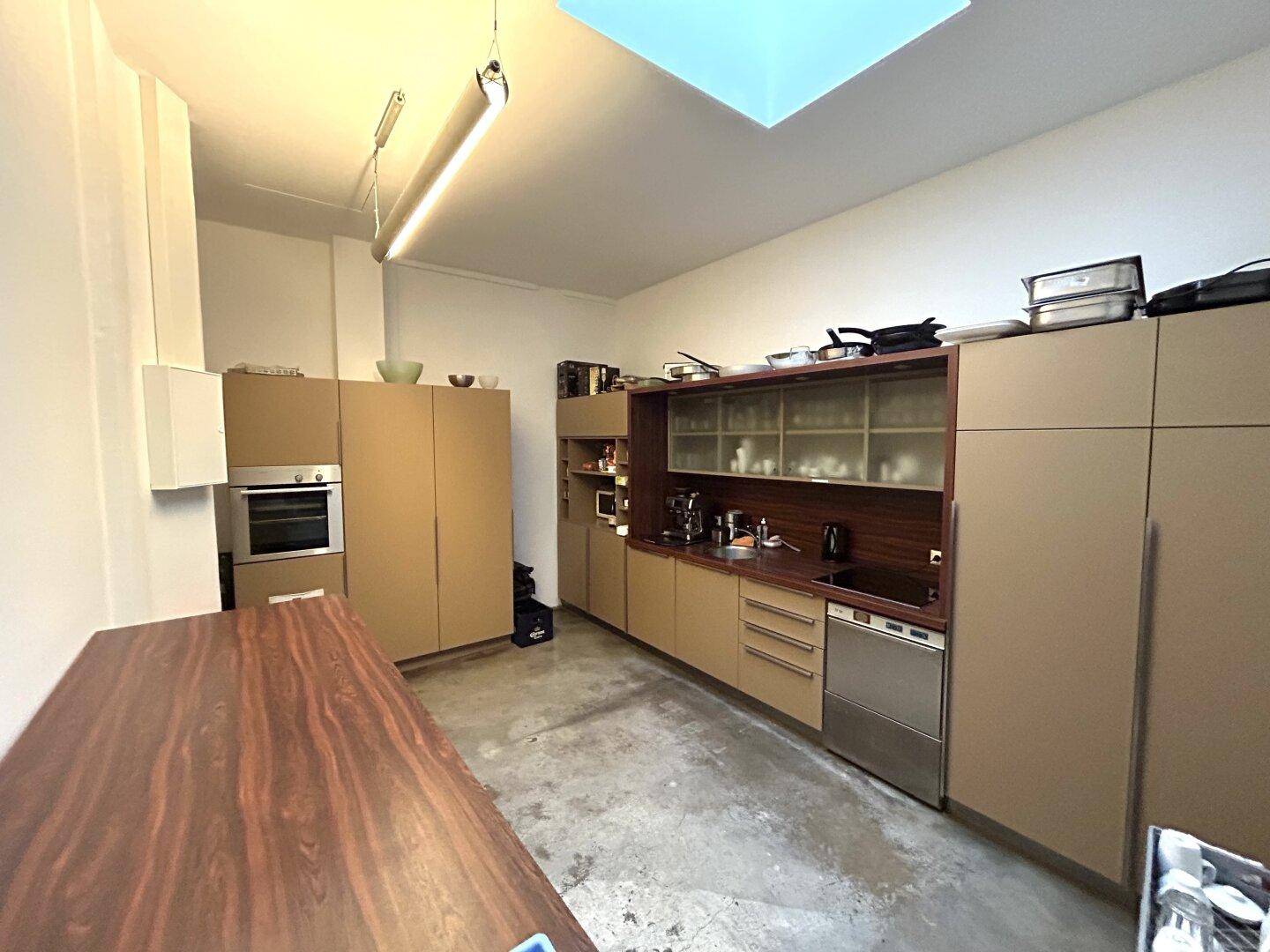Funktionale Einbauküche mit modernen Geräten, viel Stauraum und einem großen Holztisch.