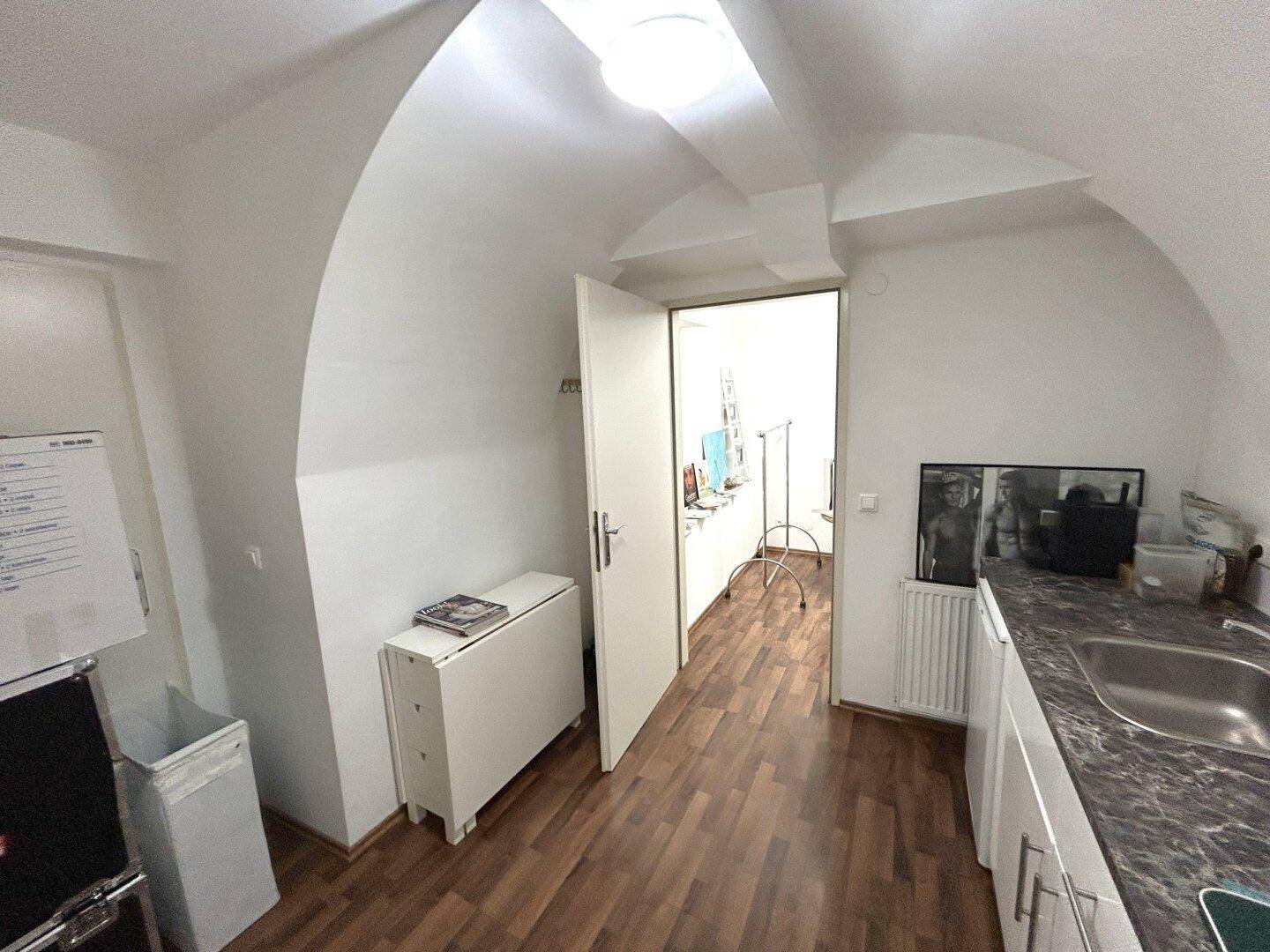 Heller Flur mit einer kleinen Arbeitsfläche, gewölbter Decke und Zugang zu einem weiteren Raum.