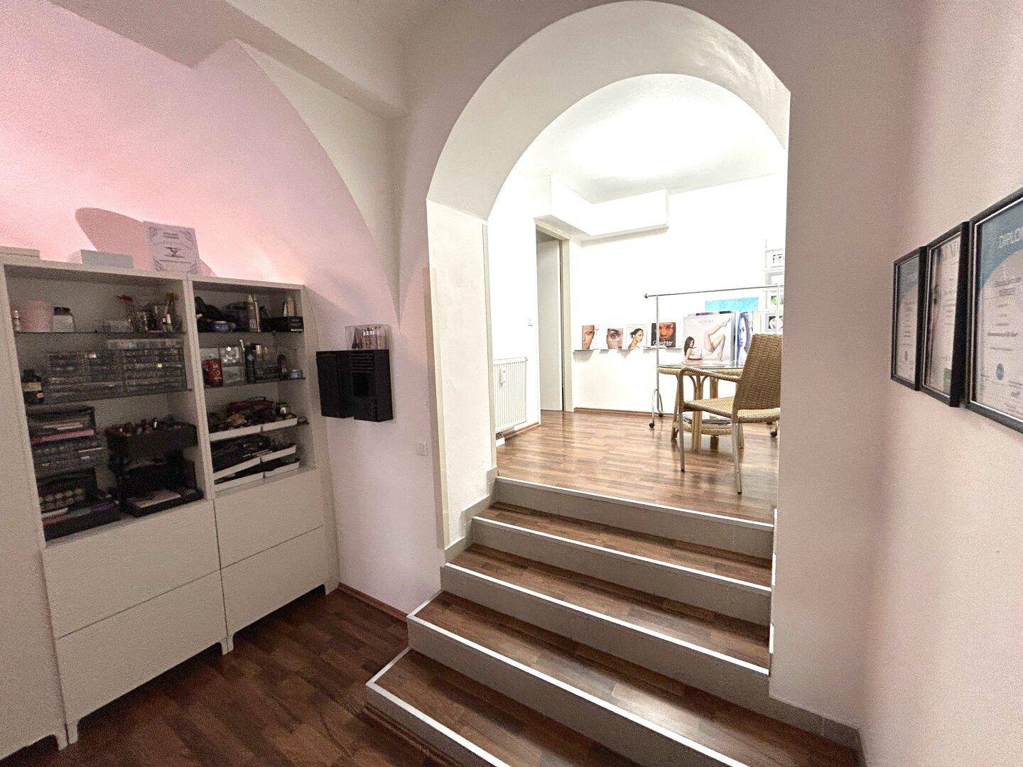 Eingangsbereich mit einer Treppe, die zu einem erhöhten Raum führt, und eleganten gewölbten Durchgängen.
