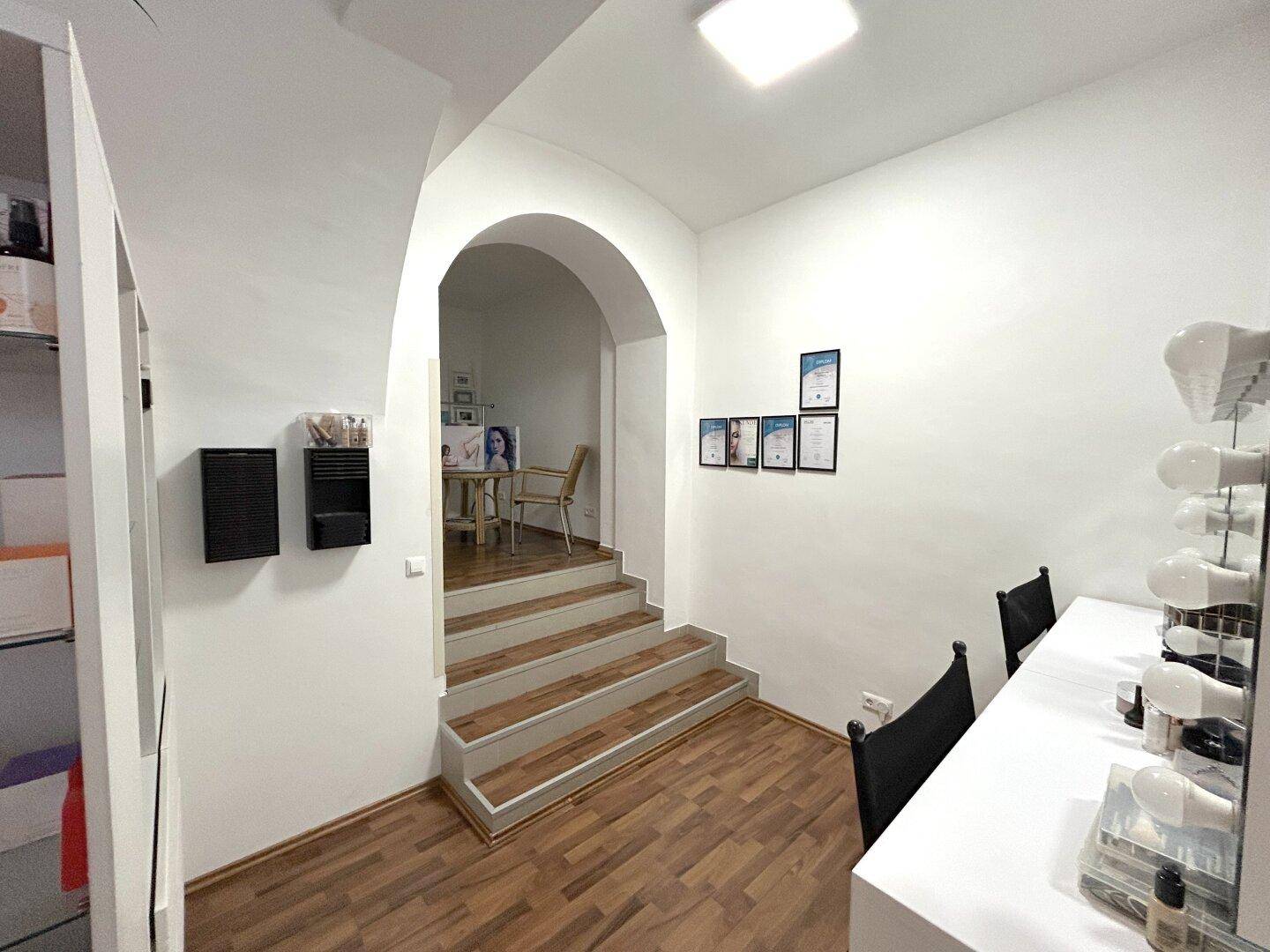 Heller Flur mit einem Schminkbereich und einer Treppe, die zu einem erhöhten Raum führt.