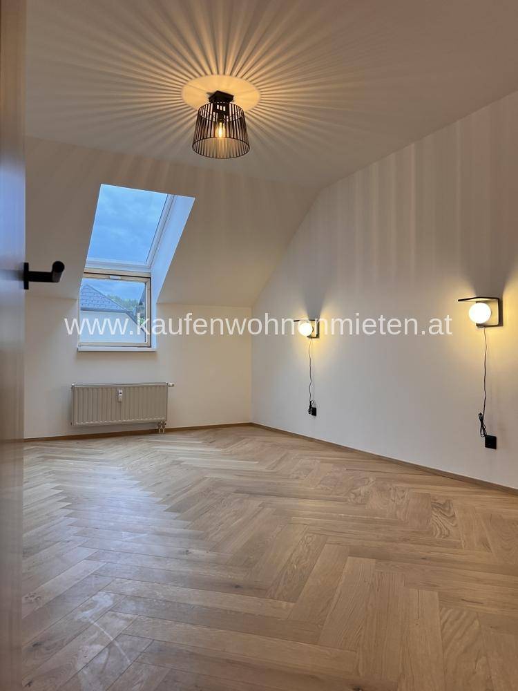 Helles Schlafzimmer im Dachgeschoss mit Dachschräge, Dachfenster und Fischgrätparkettboden.