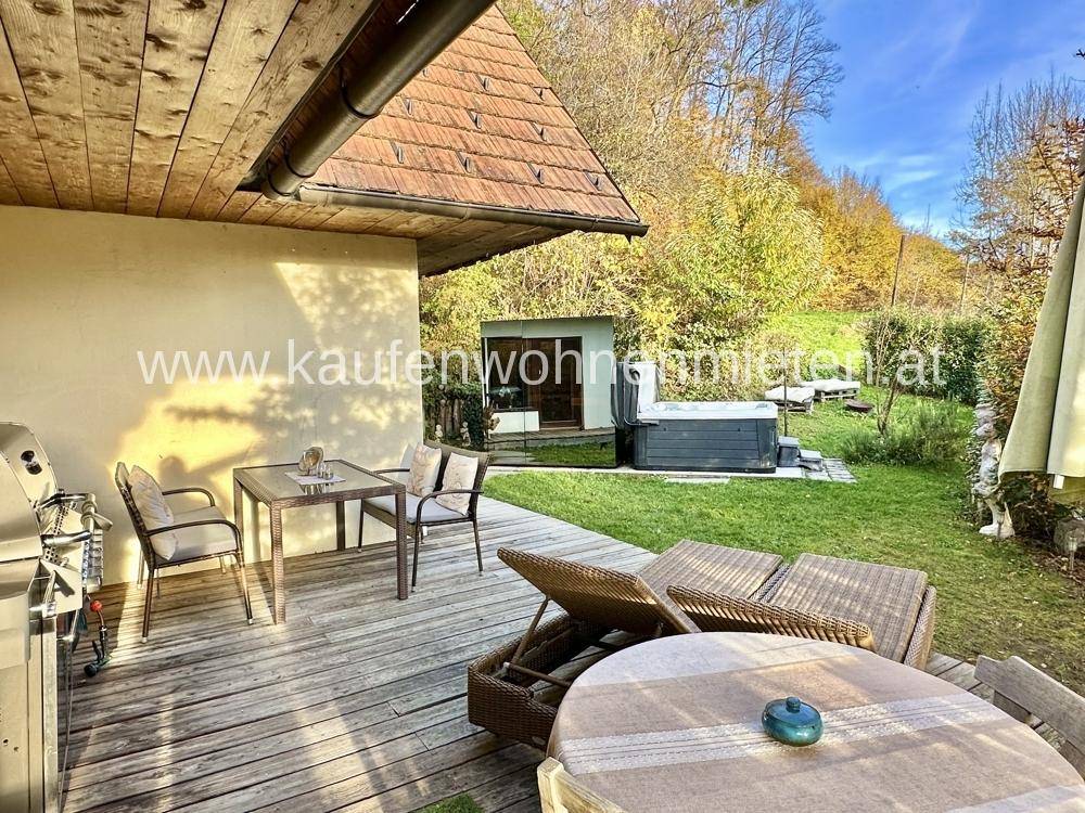 Holzterrasse mit Sitzgelegenheiten, Sonnenliegen und einem Whirlpool im Grünen.
