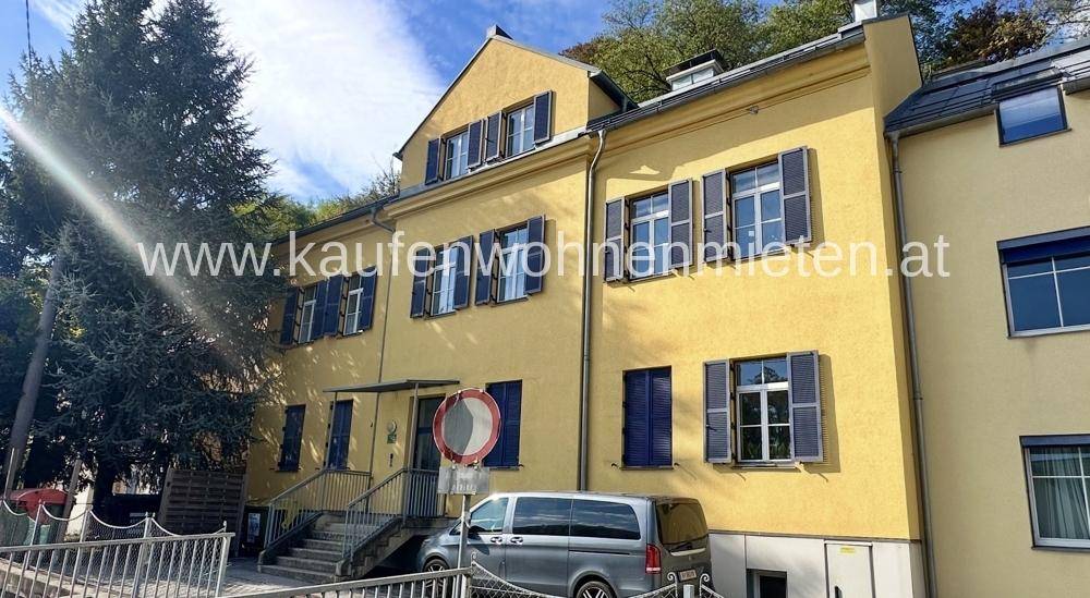 Gelbes Wohngebäude mit traditionellen blauen Fensterläden und einem geparkten Van davor.
