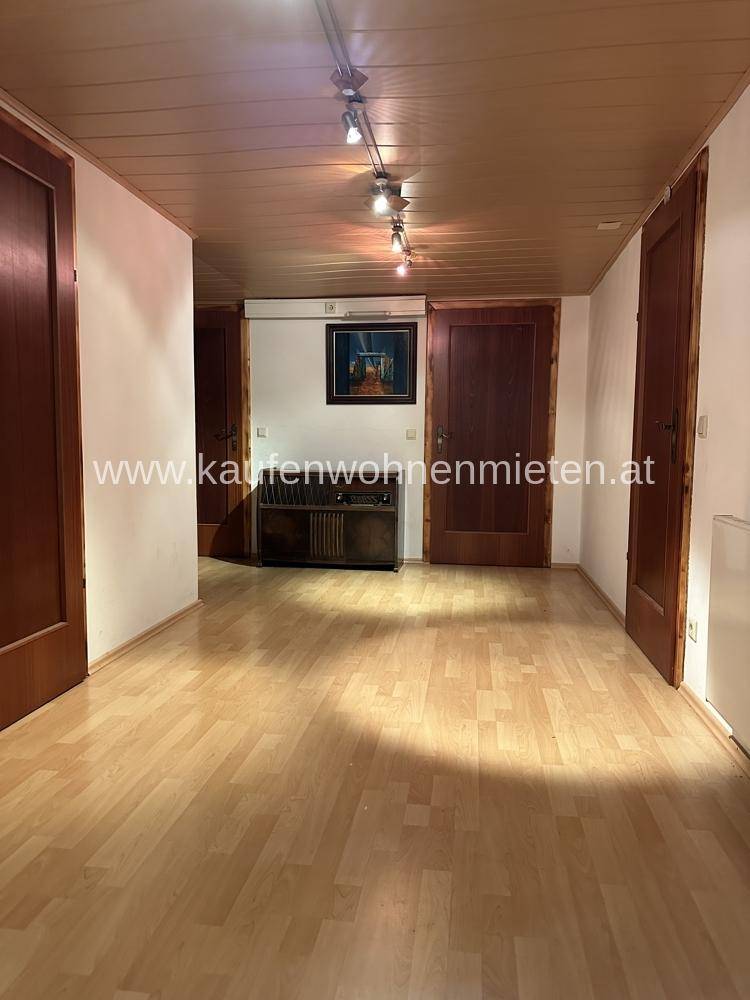 Heller Flur mit Holzdecke und Laminatboden, verbindet verschiedene Räume im Haus.