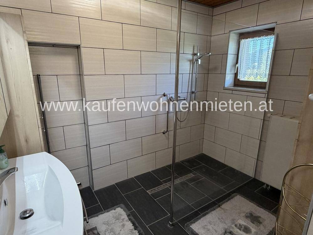 Modernes Badezimmer mit begehbarer Dusche, großformatigen Fliesen und Fenster.