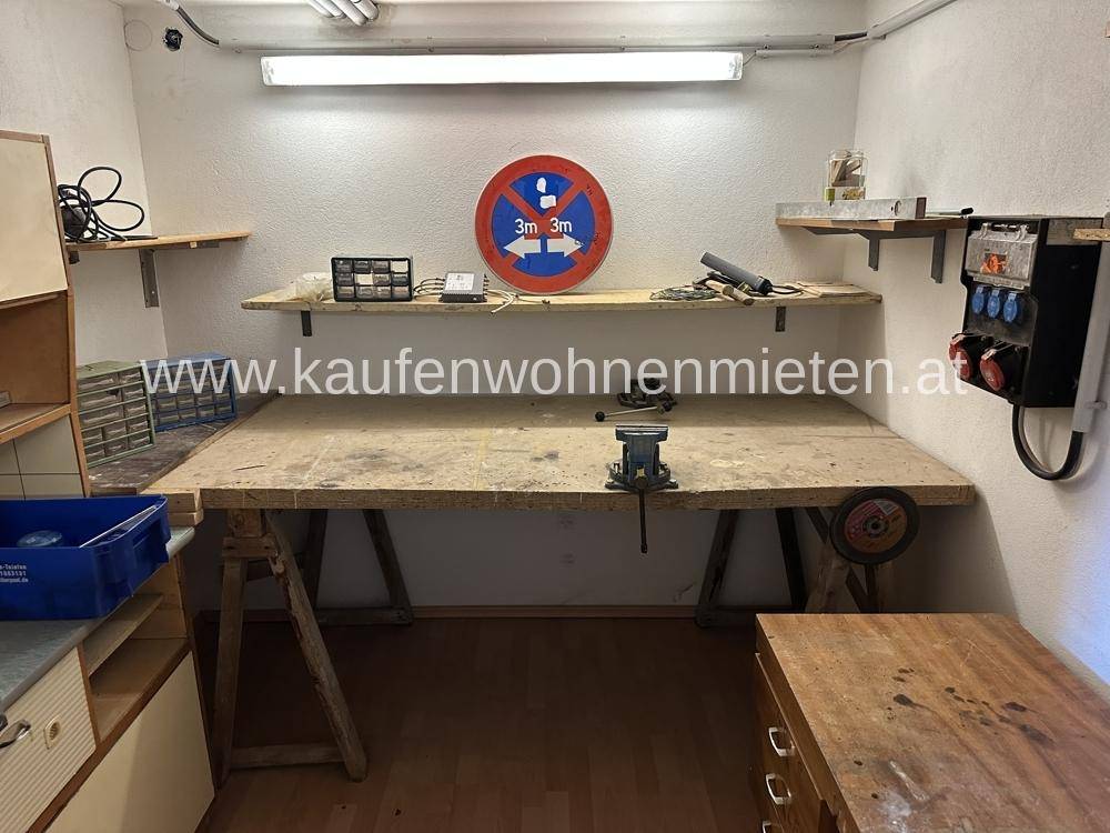 Werkstatt mit großer Werkbank, Regalen und Beleuchtung, ideal für handwerkliche Arbeiten.